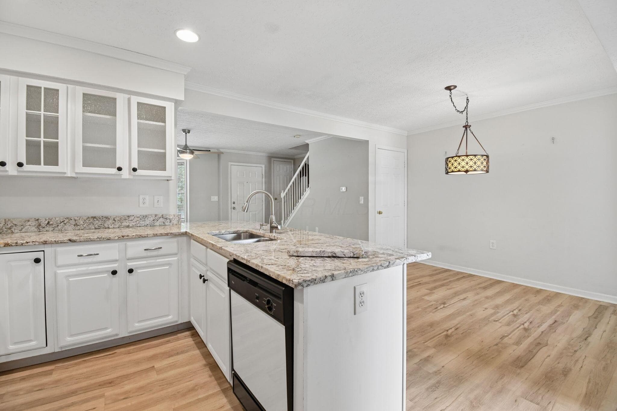 White cabinetry with glass-front uppers, granite countertops, wood-finish flooring, and a contemporary chandelier