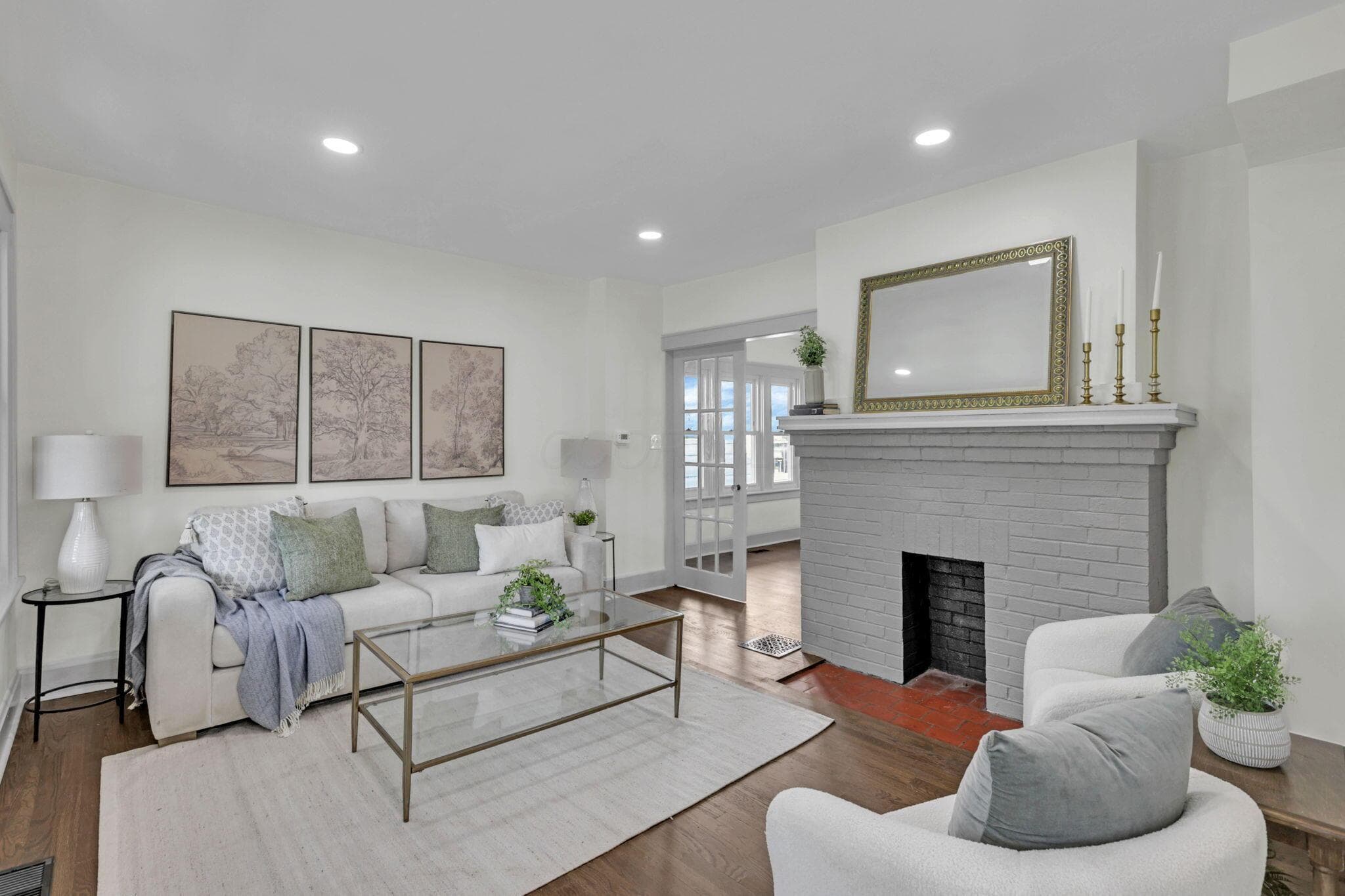 Warm wood-finish flooring complements the brick-clad fireplace with a substantial mantel