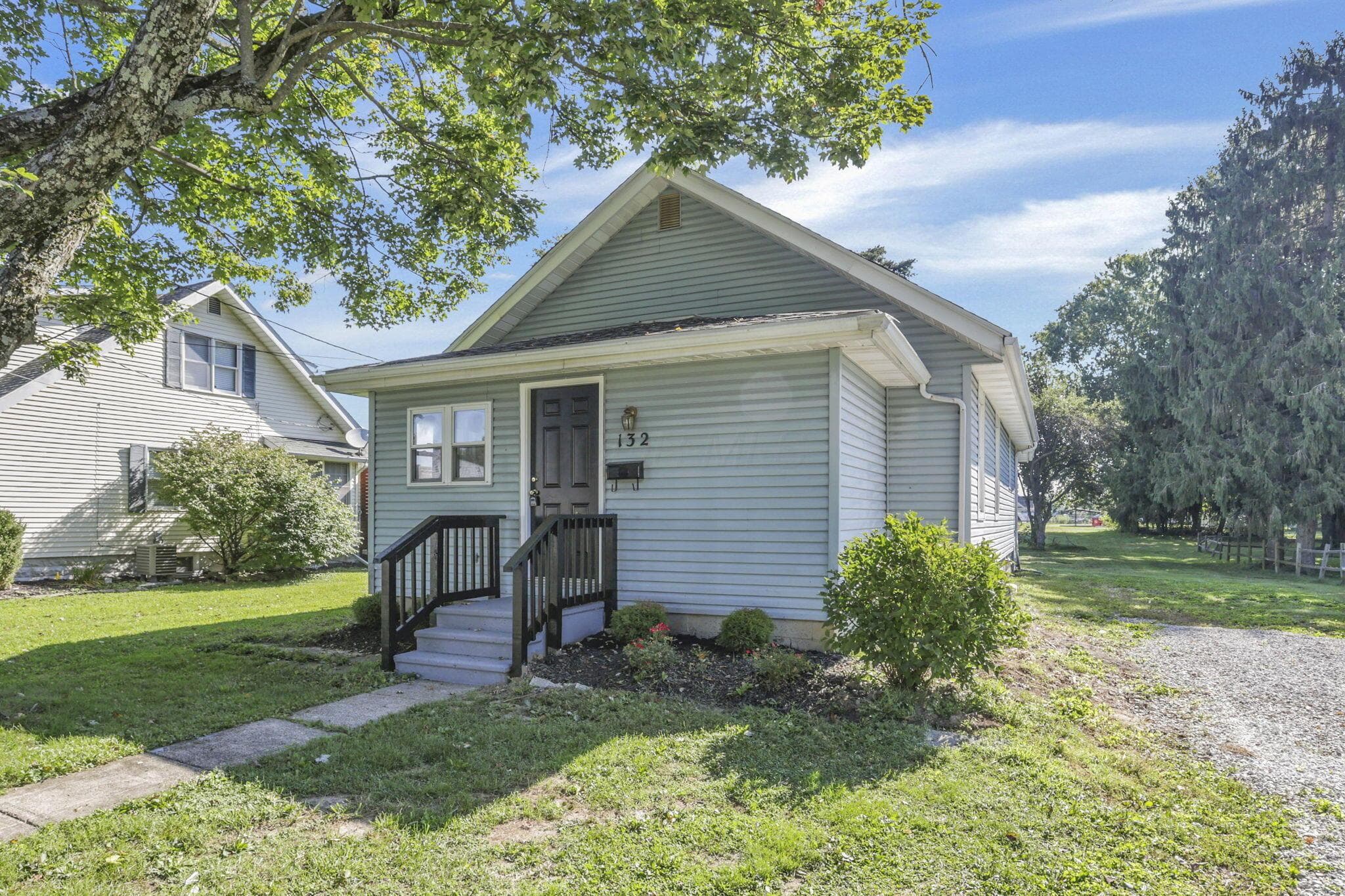 Siding exterior with a covered entry and dark wood-finish railing