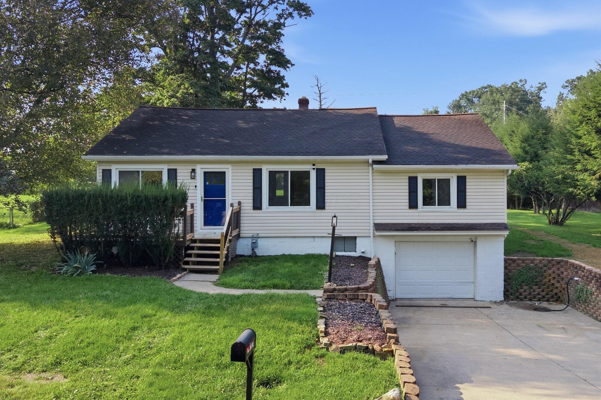 Single-family residence with light-toned siding, a dark shingle roof, and a prominent attached garage