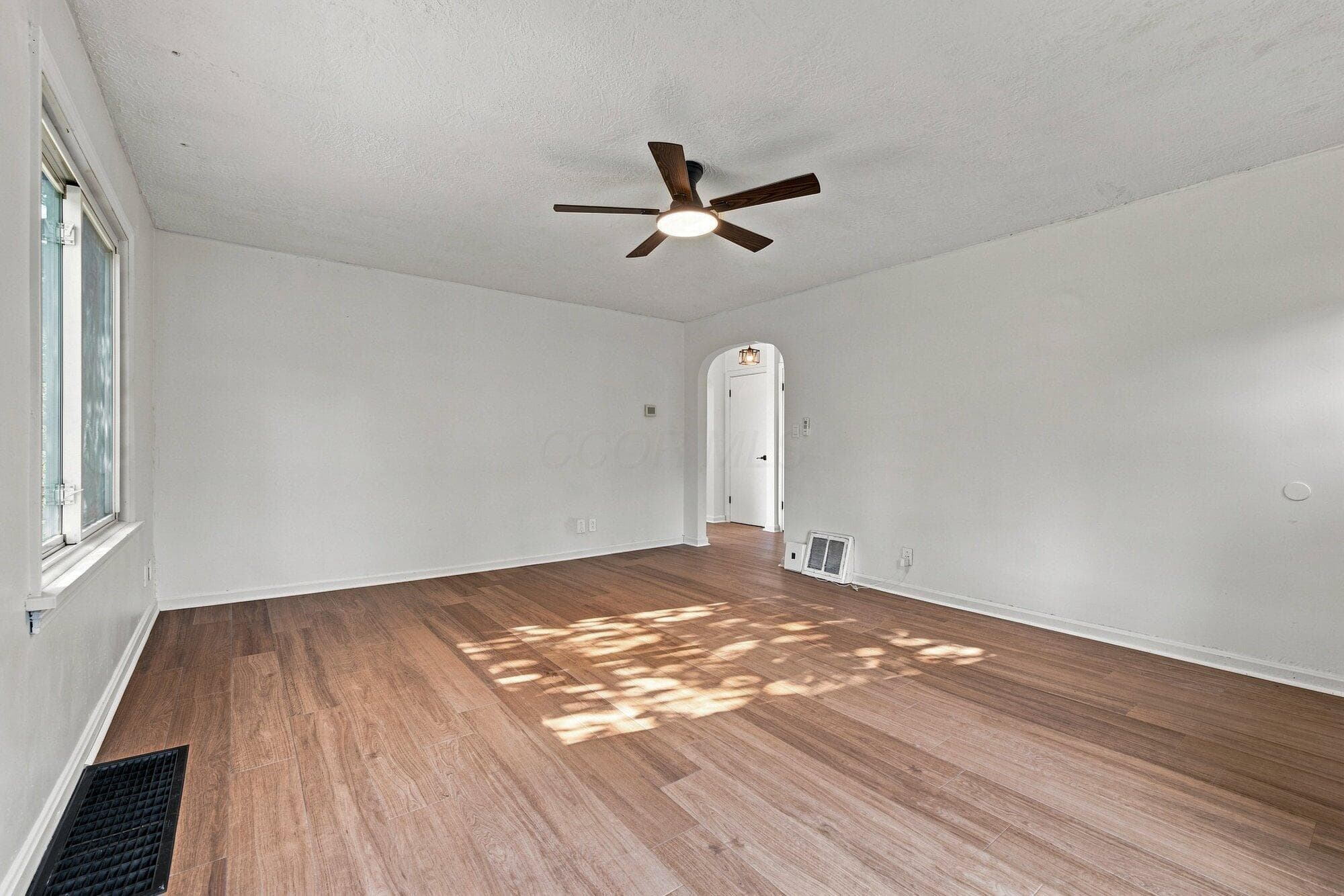 Wood-finish flooring with crisp white walls, illuminated by natural light from the window
