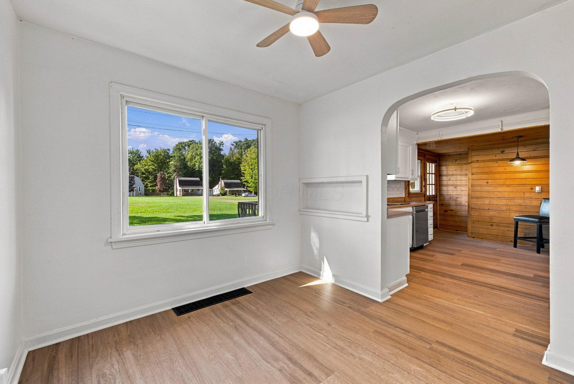 Wood-finish flooring throughout, with an arched doorway and a ceiling fan with integrated lighting
