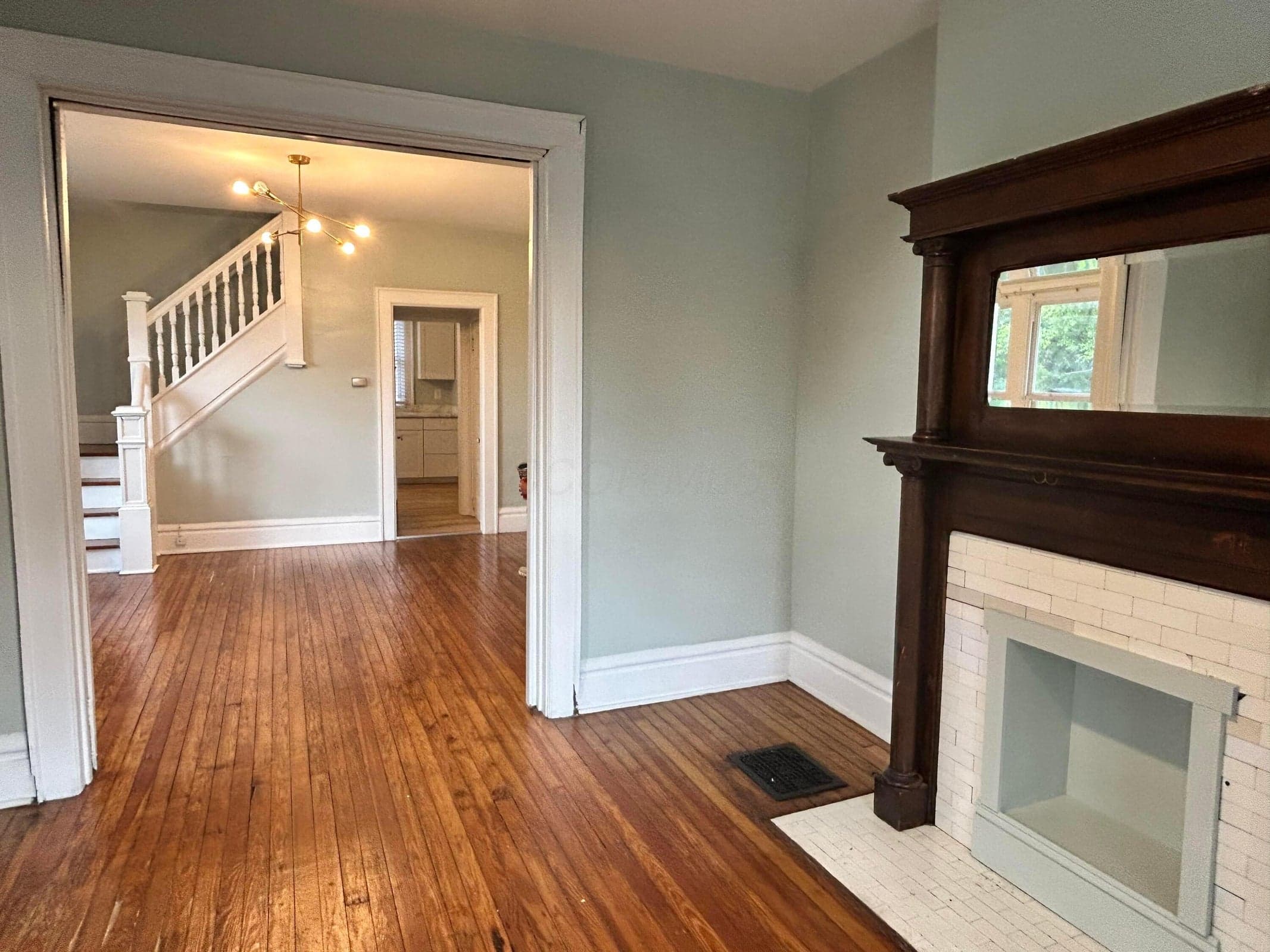 28- Hardwood flooring throughout, decorative fireplace with mantel, white trim, and a staircase with white balusters
