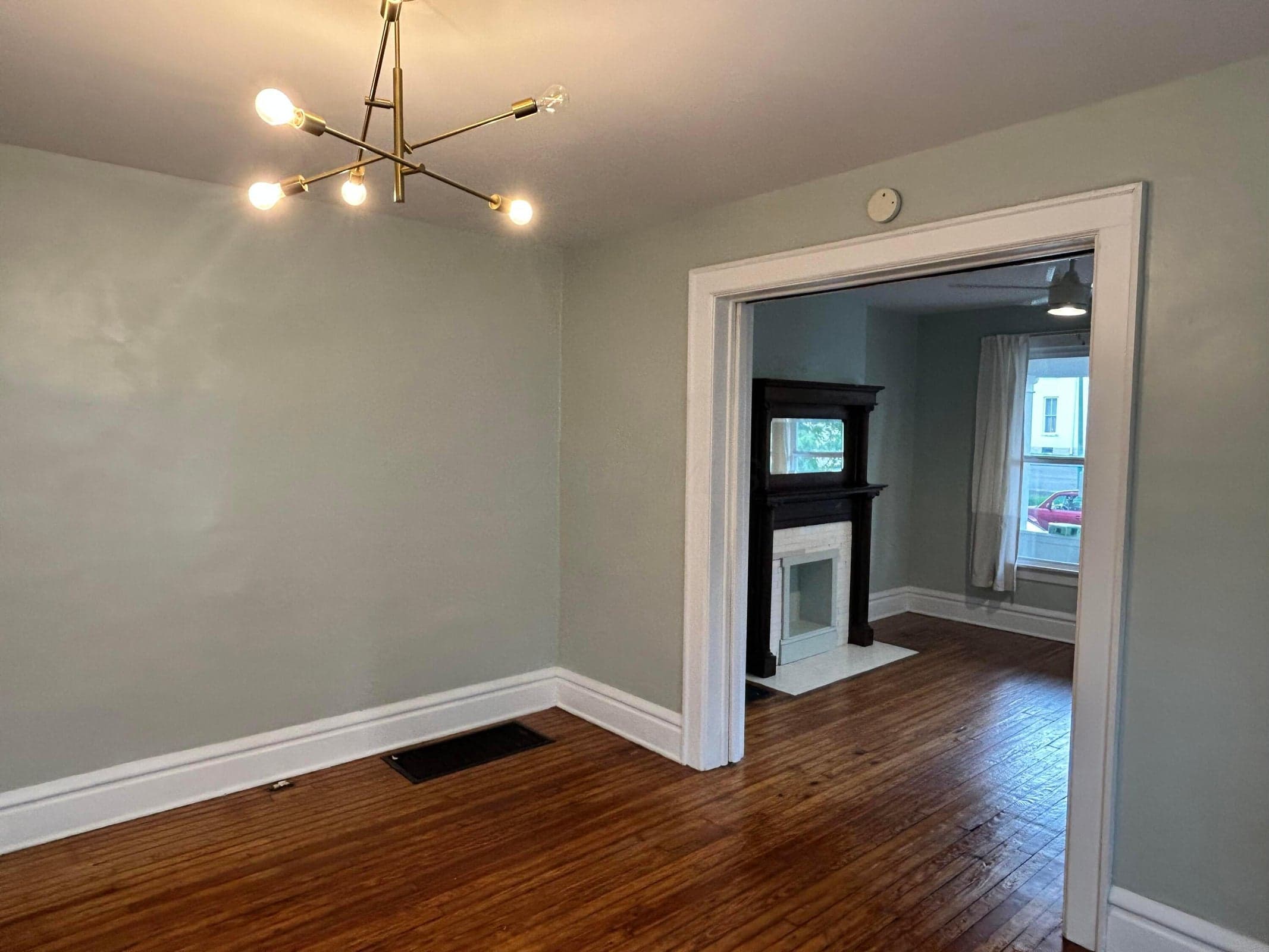 28= Wood flooring, contemporary chandelier, wide doorway, and a decorative fireplace