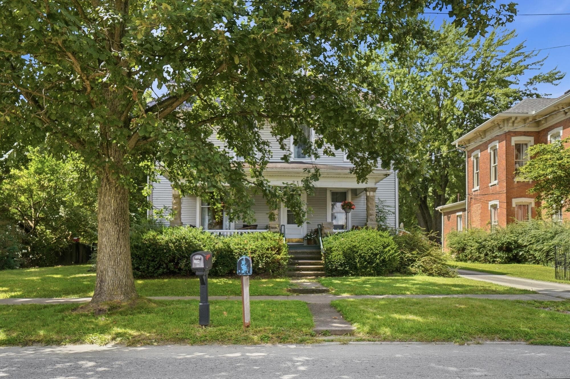 White siding exterior with a covered front porch and mature trees