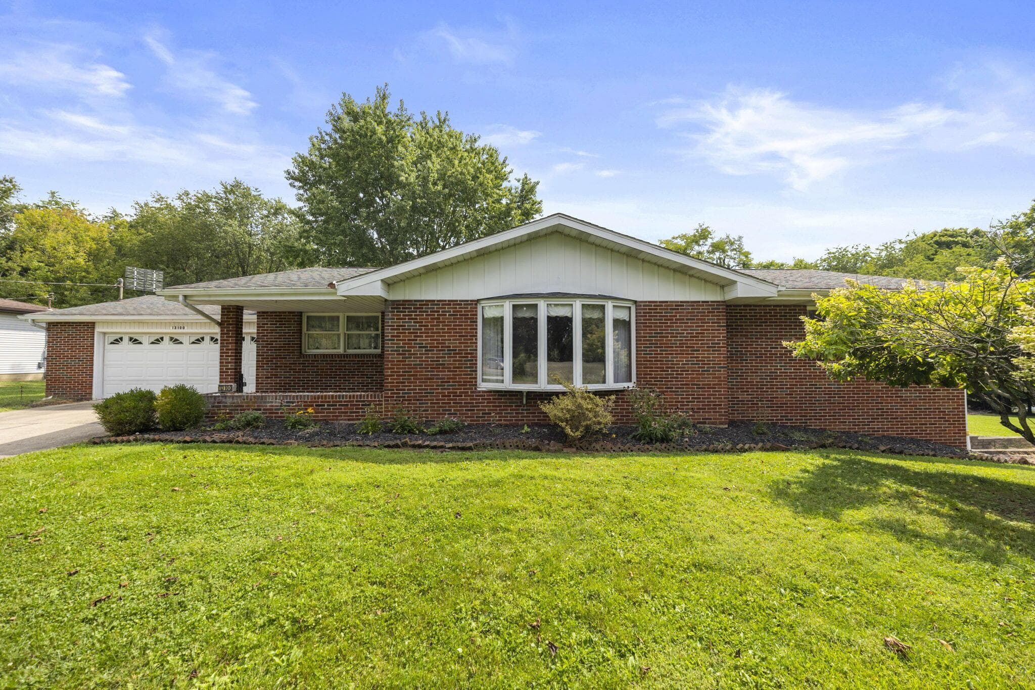 Brick exterior with white trim, featuring a bay window and an attached garage