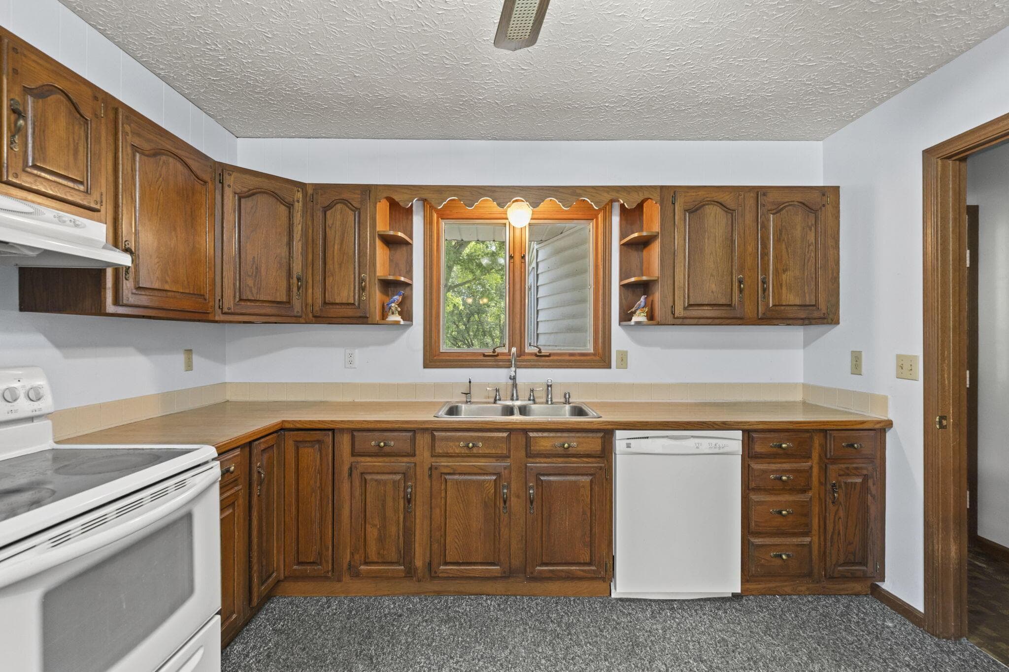 Wood-finish cabinetry with a built-in dishwasher, stainless steel double basin sink, and laminate countertops
