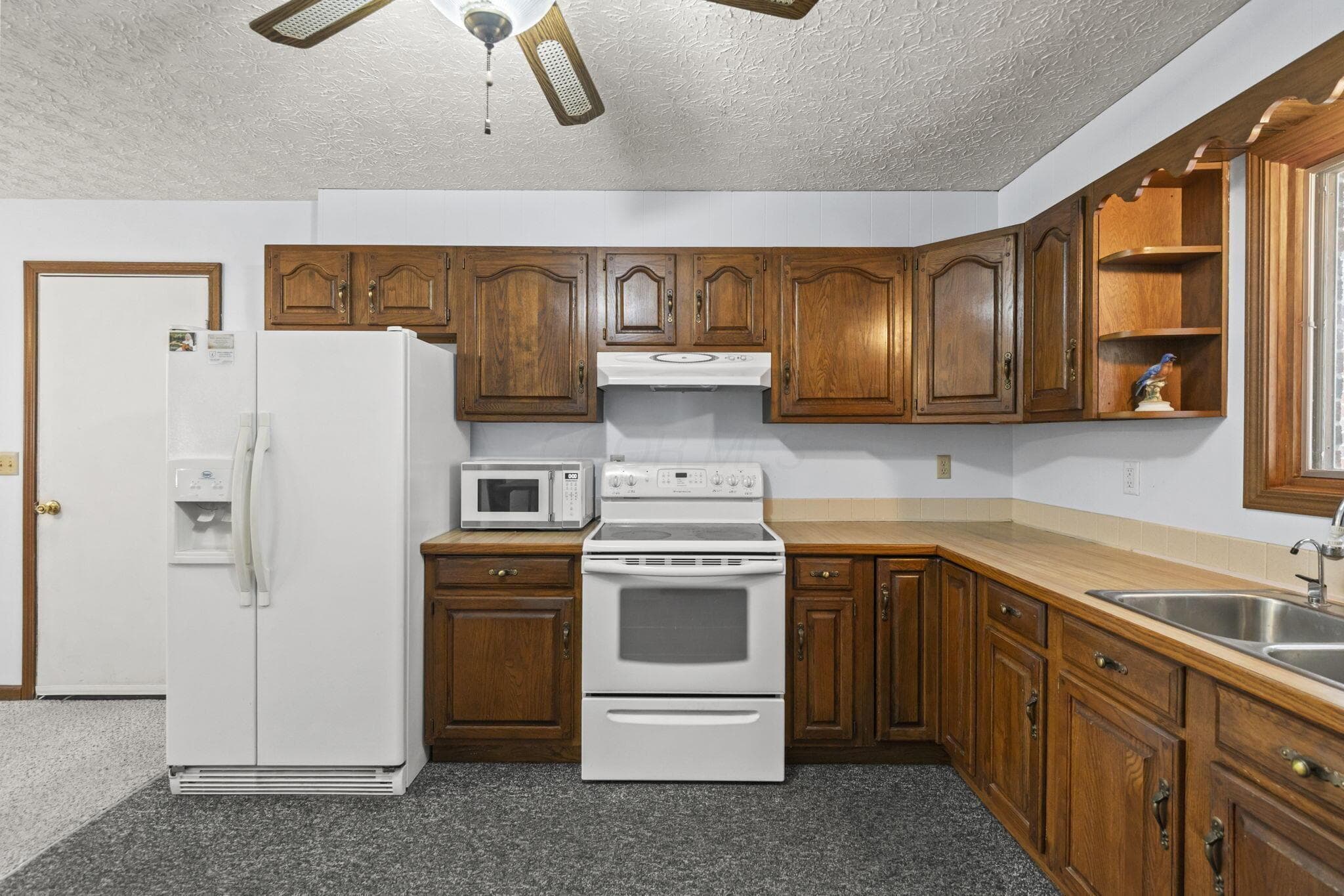 Kitchen featuring wood cabinetry, laminate countertops, a double basin sink, and a ceiling fan
