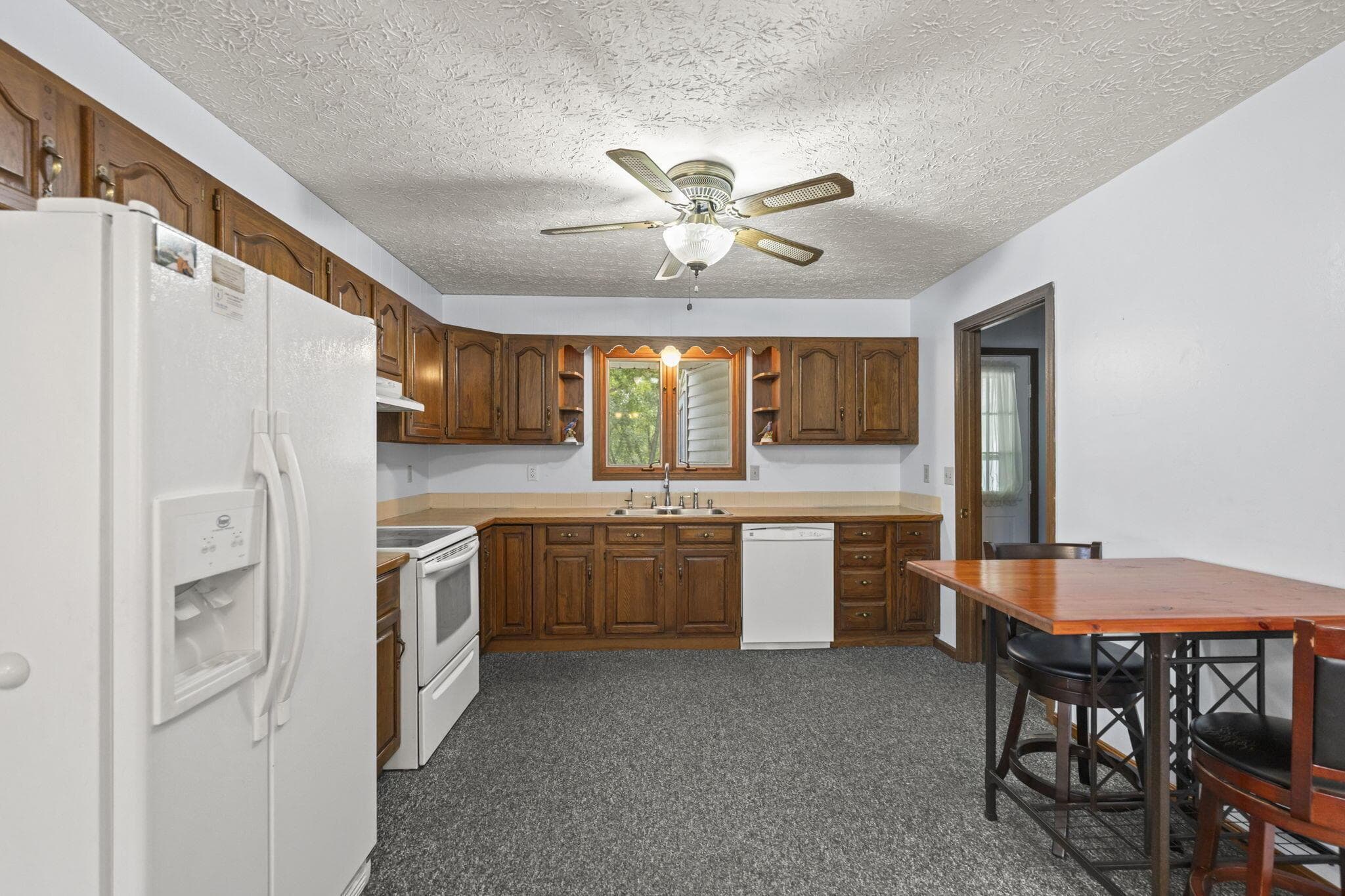 Kitchen featuring wood cabinetry, white appliances, and a window above the sink for beautiful view of the private backyard
