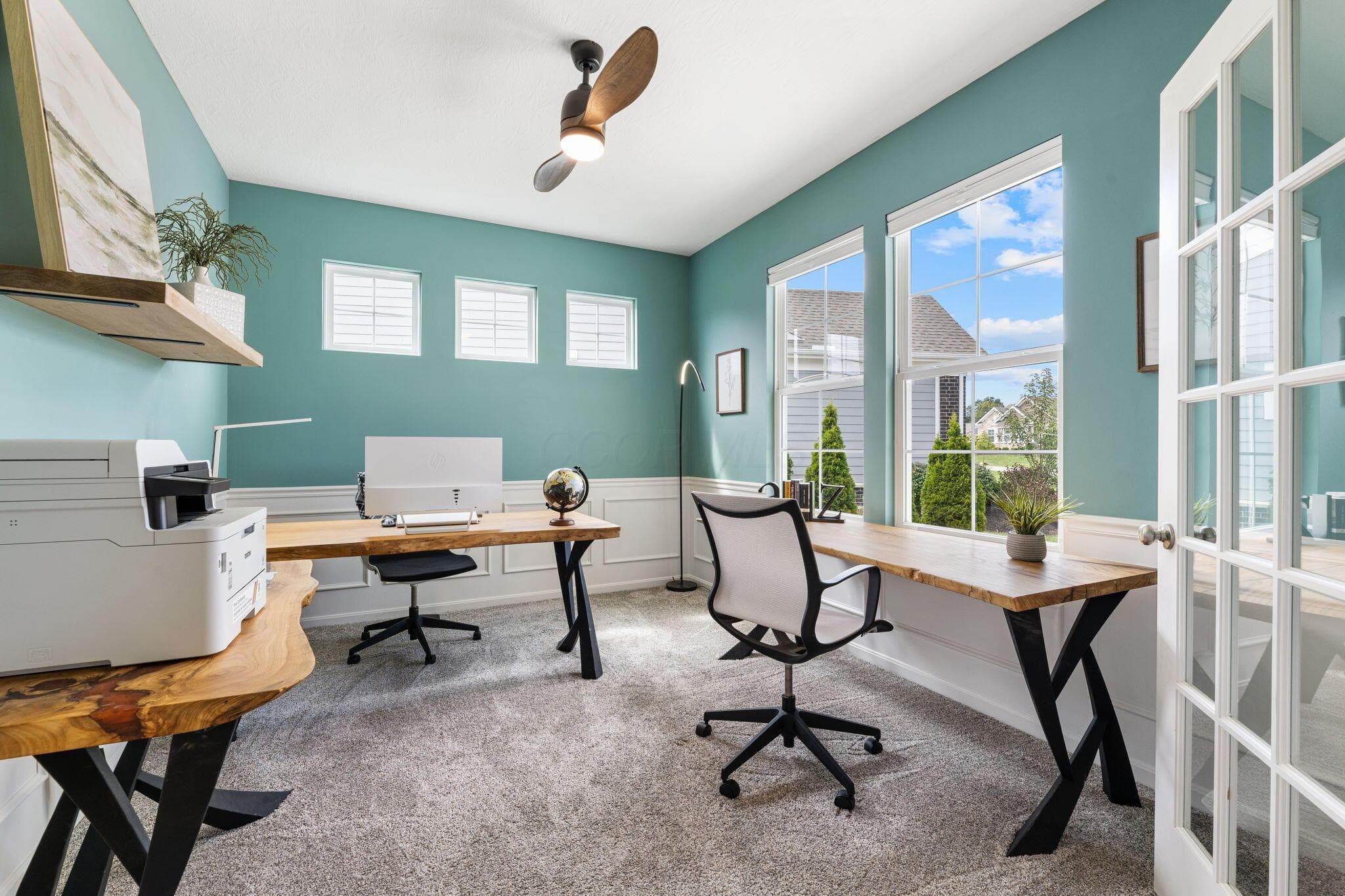 Room featuring a vaulted ceiling with a ceiling fan, wainscoting, and large windows