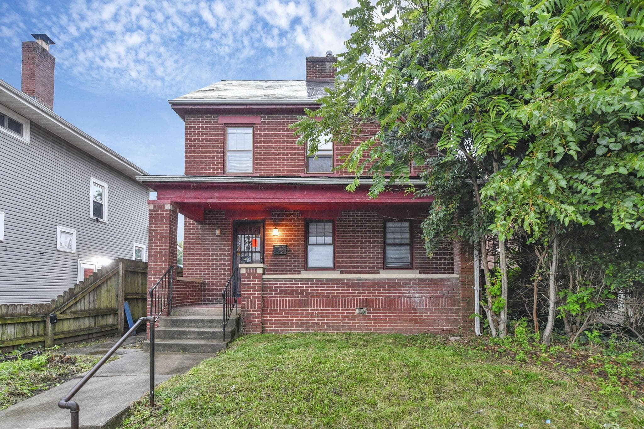 Brick exterior facade with a covered porch and concrete steps