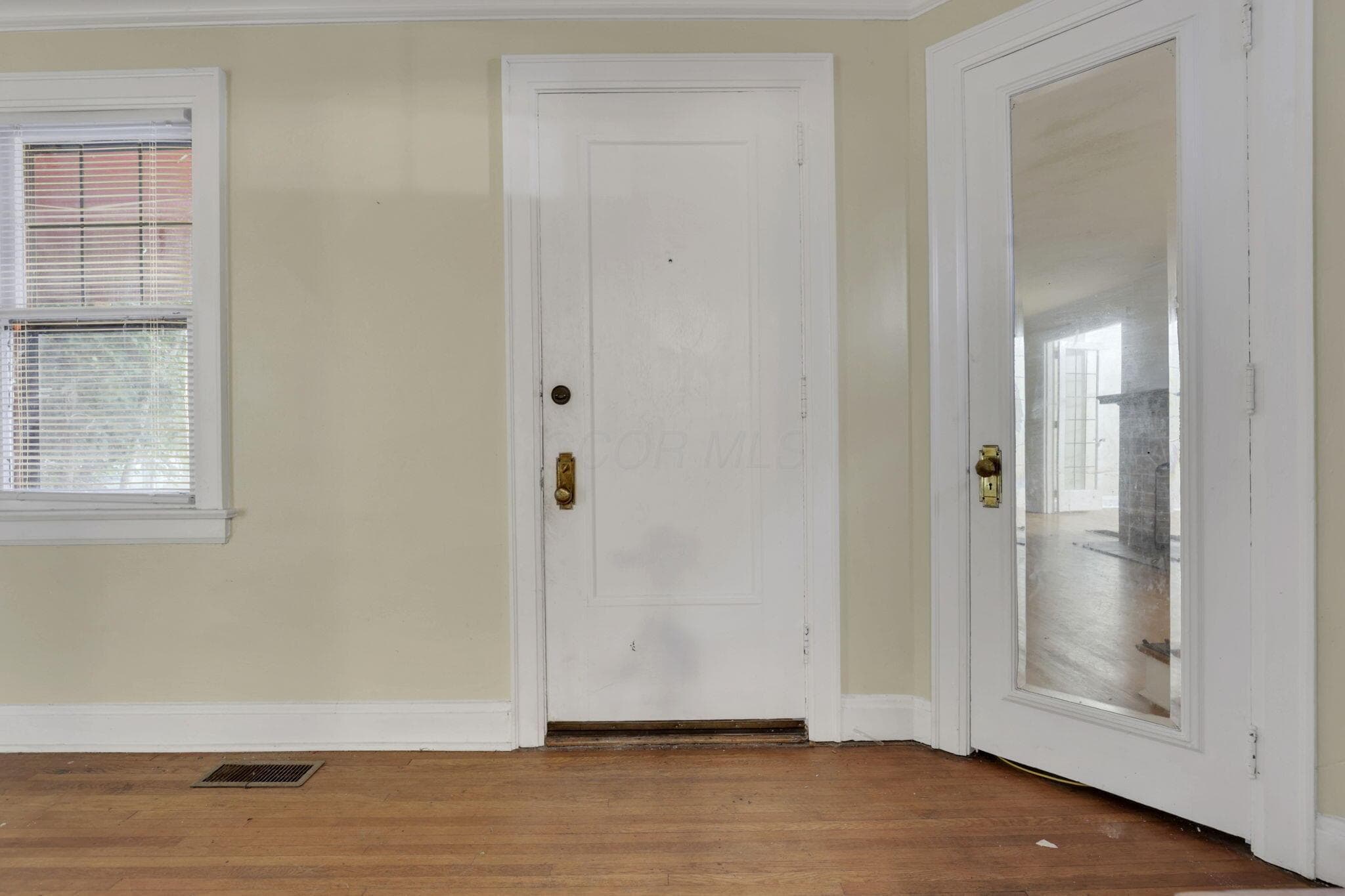 Hardwood-style flooring, white trim details, panel door with brass hardware, glass-paneled interior door
