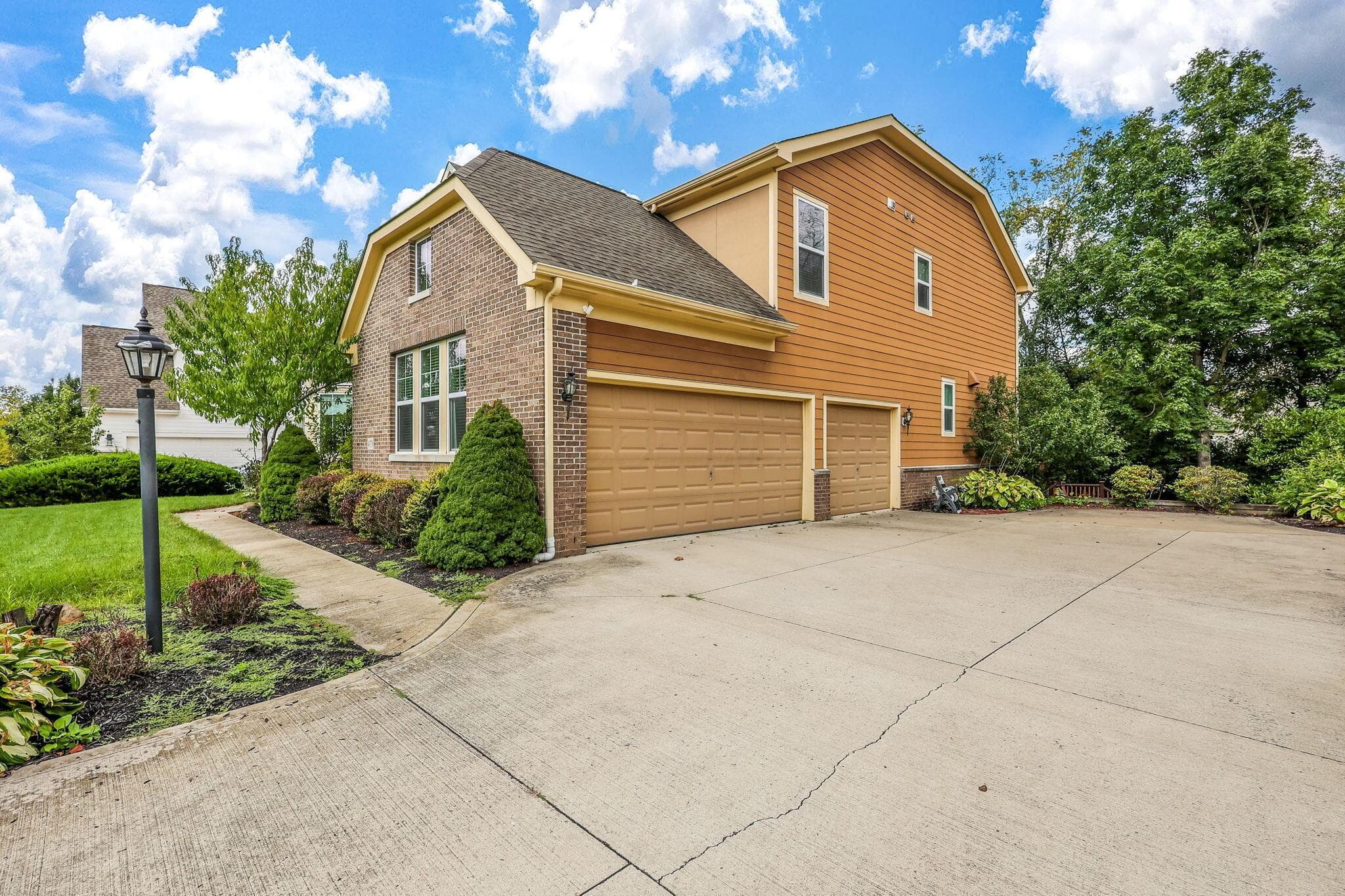 Brick and siding exterior with a multi-car concrete driveway