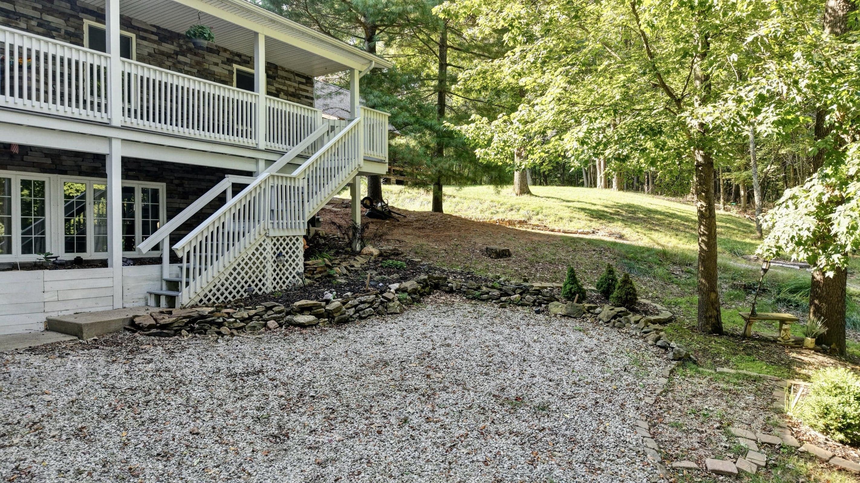 Stone-clad exterior with white fenestration, dual-level covered porch, and white wooden railings