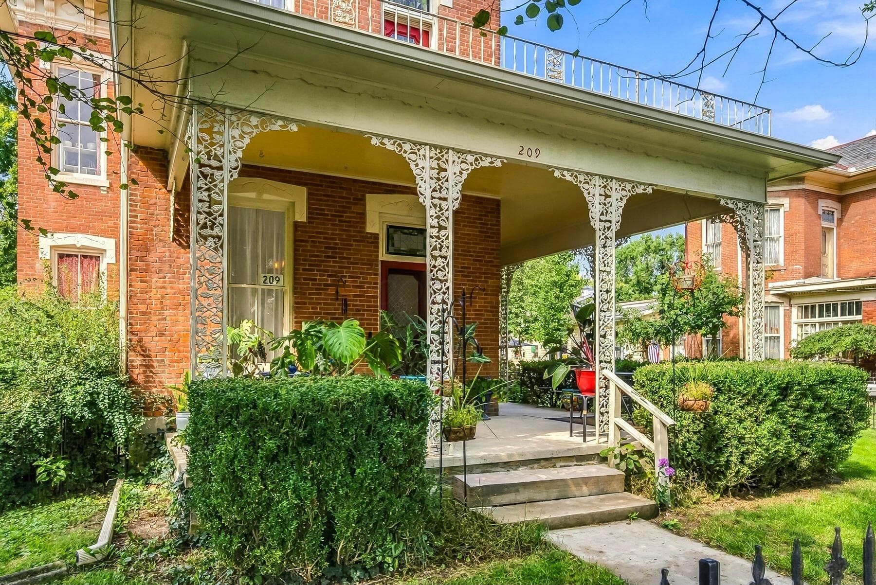 Charming covered wrap-around porch with decorative ironwork.