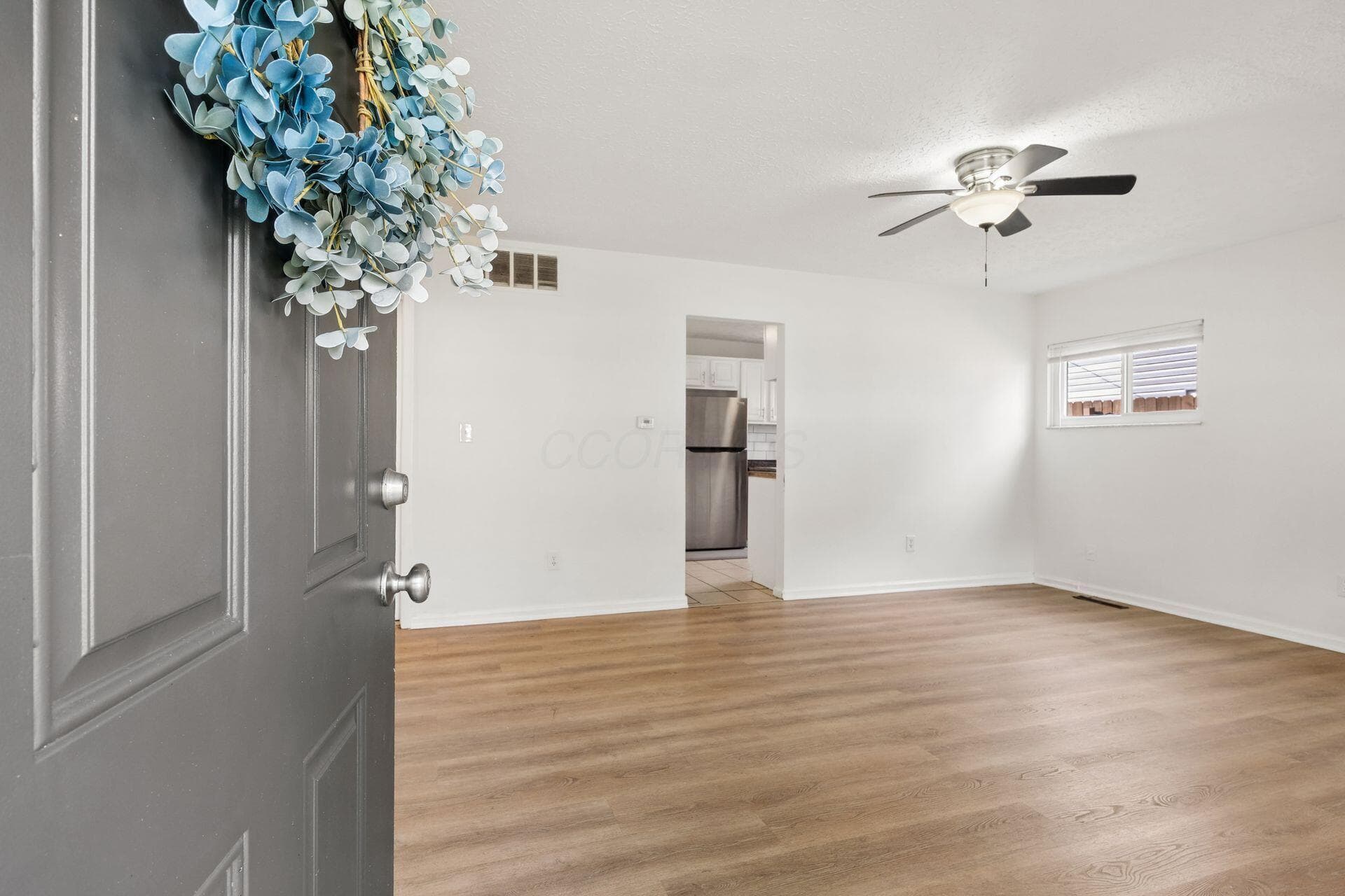 Wood-finish flooring throughout, bright white walls, and a contemporary ceiling fan with integrated lighting