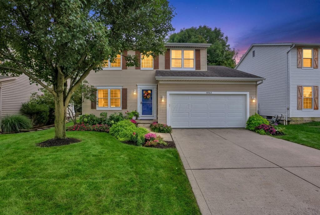 Two-story residence with a two-car garage, concrete driveway, and gorgeousfront landscaping