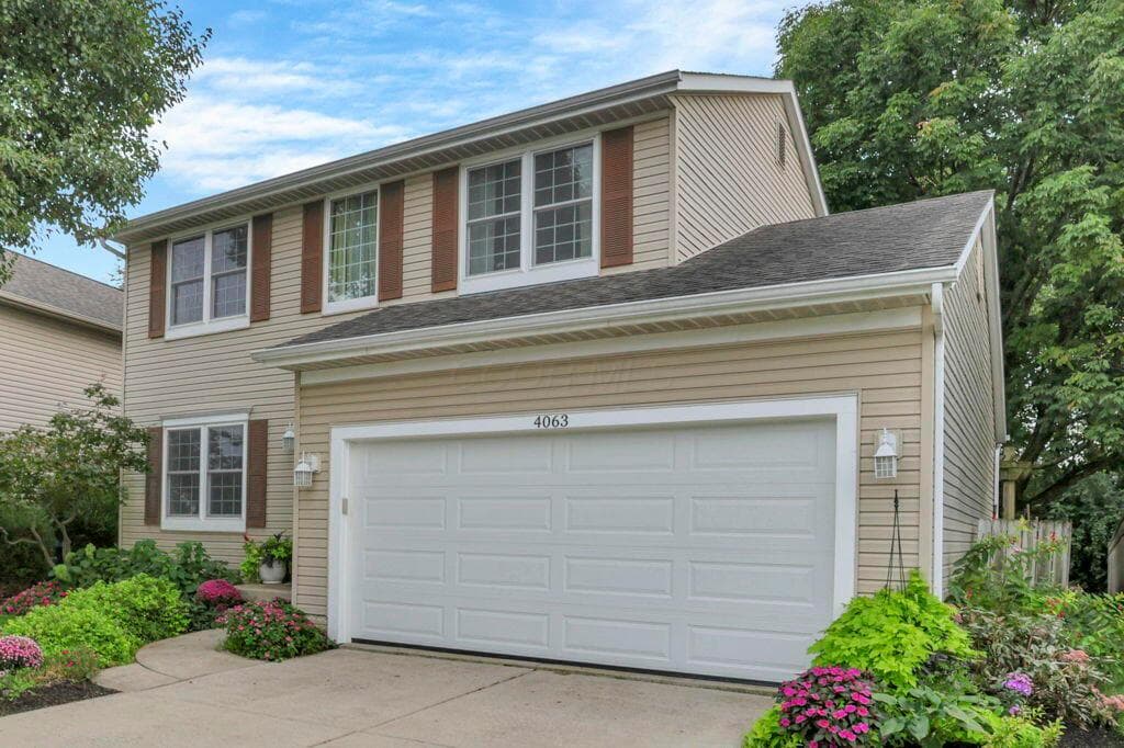 Two-story residence featuring light-colored siding, a two-car garage, and a concrete driveway