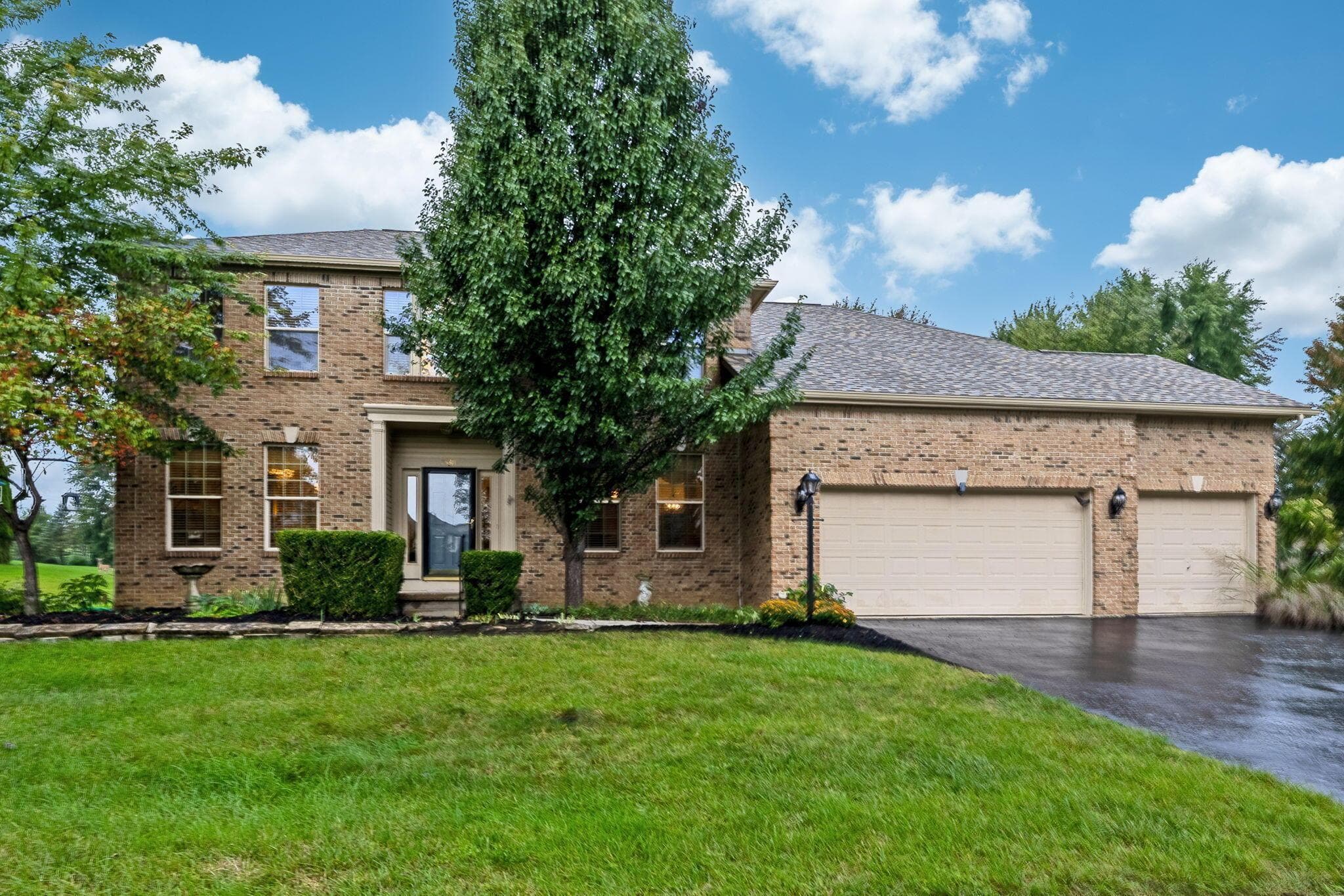 Brick exterior, two-story structure, two-car garage, mature landscaping, paved driveway