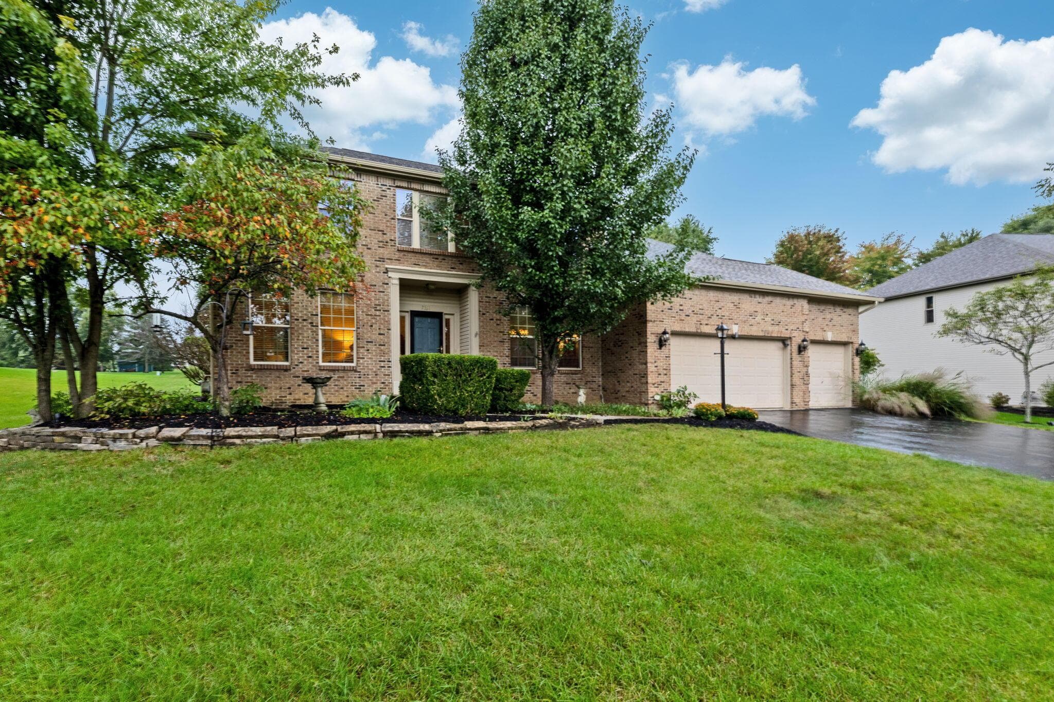 Brick exterior with an established landscape, a full-size driveway, and a two-car garage