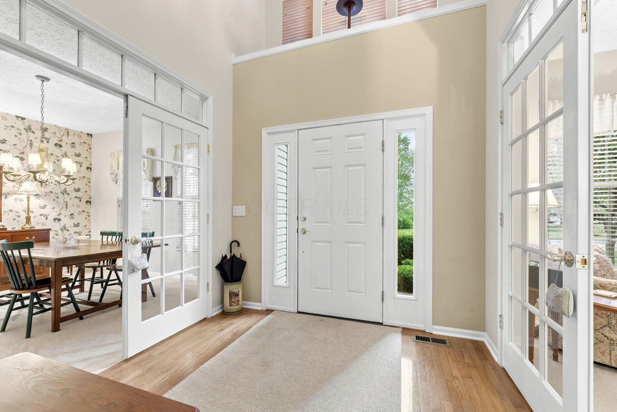 Vaulted entry featuring wood-finish flooring, a neutral wall palette, and a white paneled door with sidelights