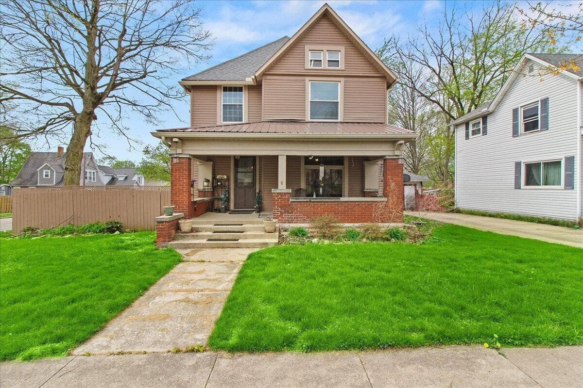 Traditional-style residence with a covered front porch featuring brick pilasters and base