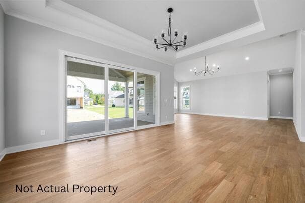 Expansive room featuring wood-finish flooring, and a tray ceiling.
