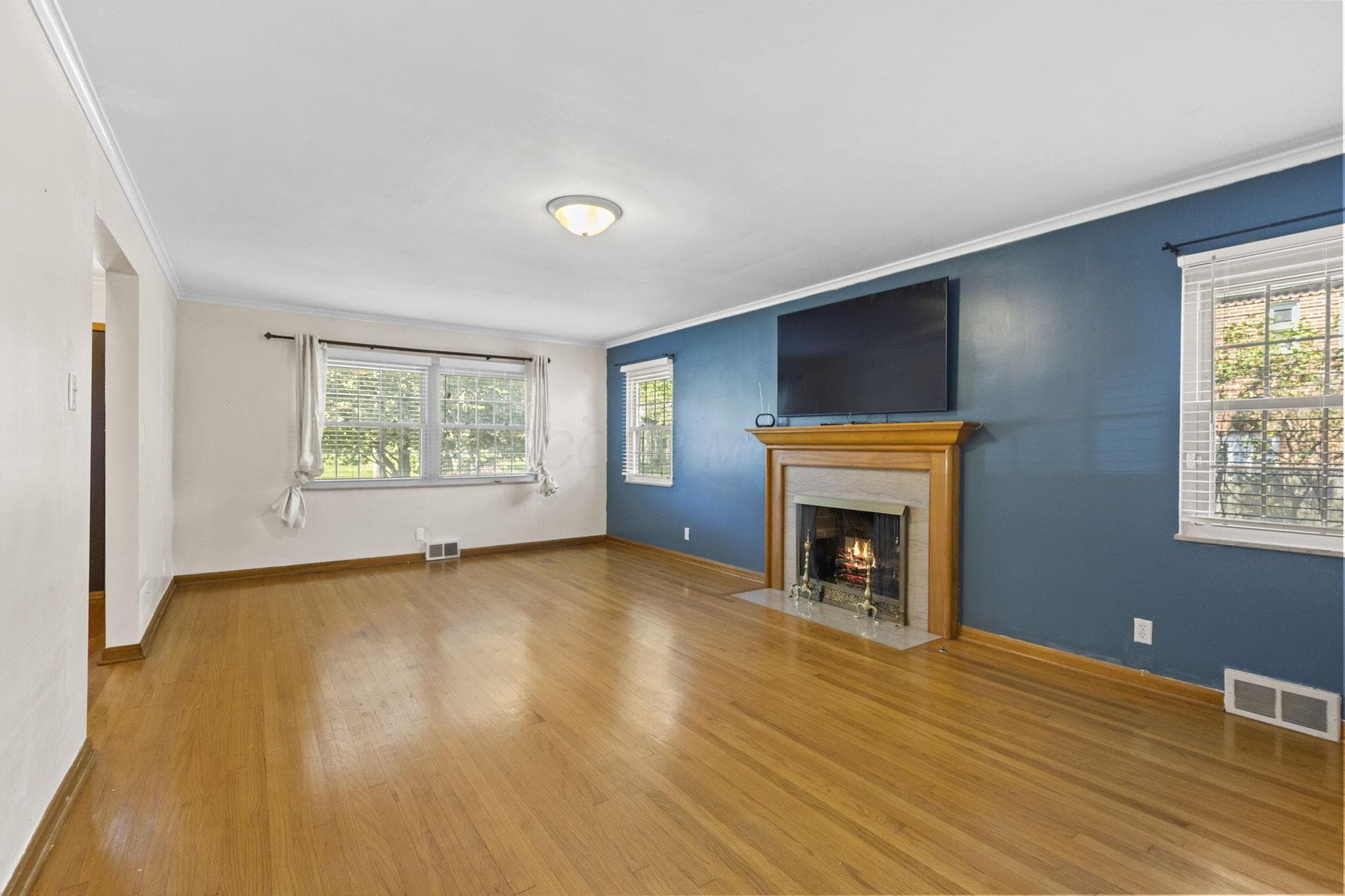 Hardwood flooring, crown molding, fireplace with mantel, recessed fireplace insert, and multiple windows