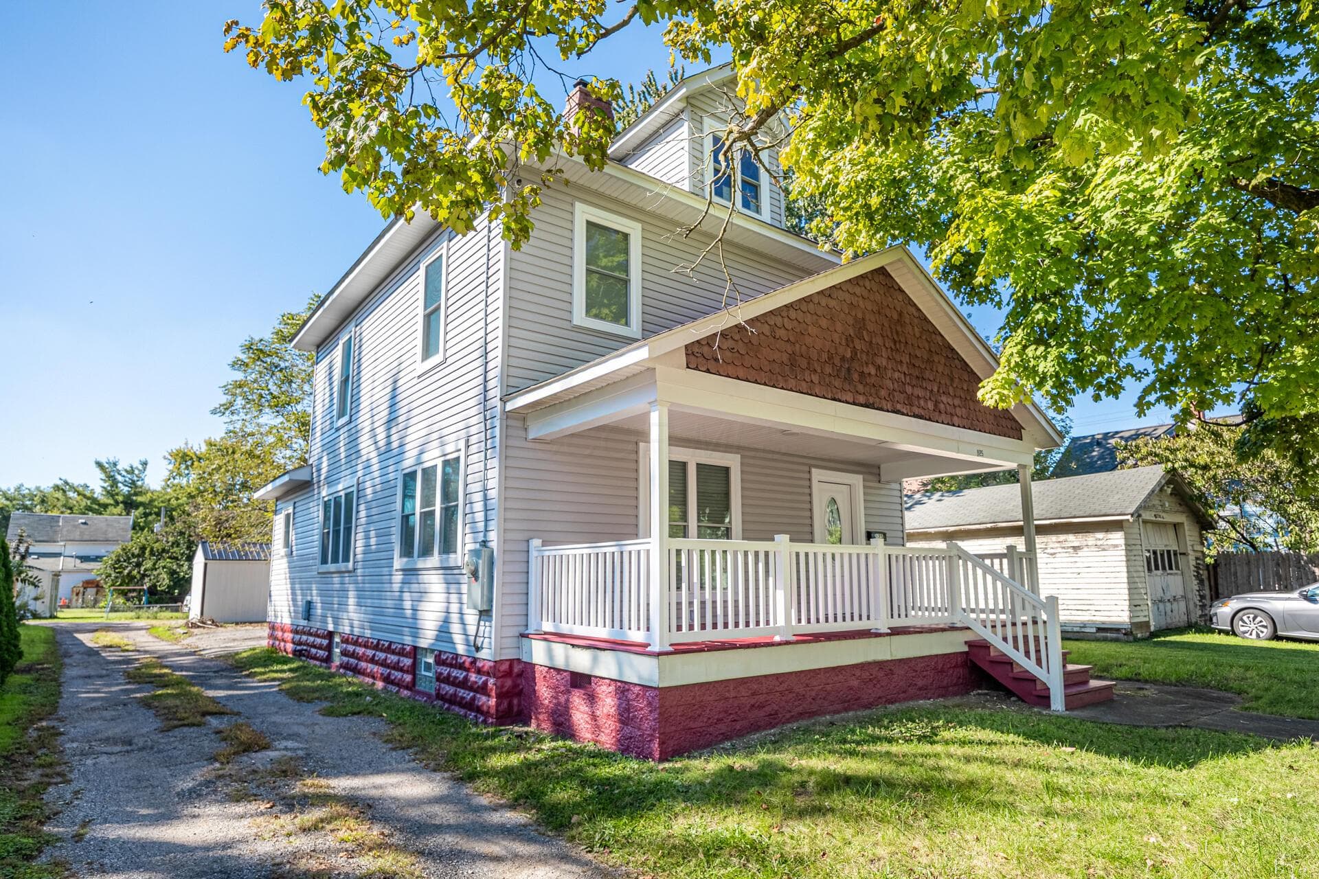 Two-story residence with light-colored siding and a covered front porch featuring white railings