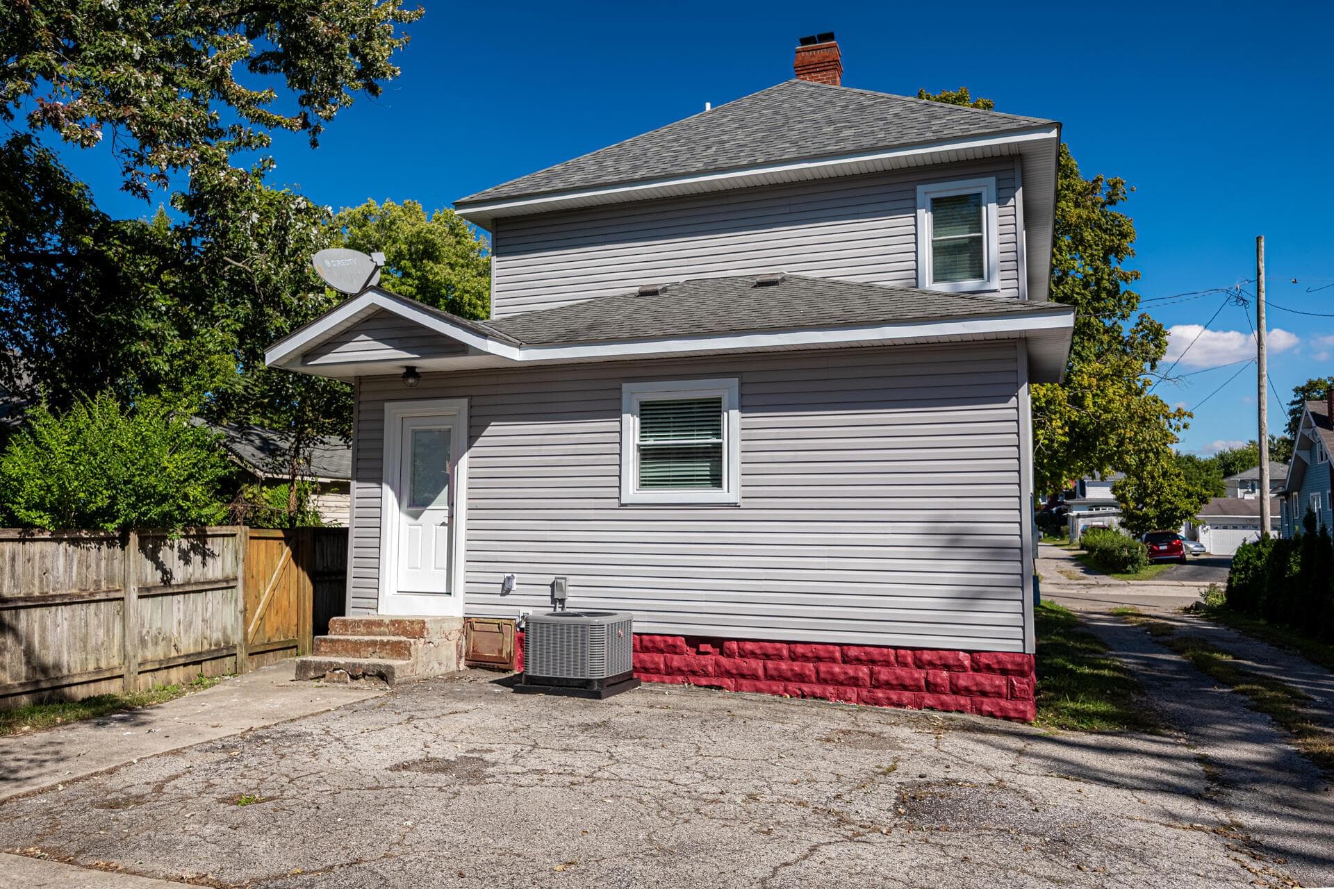 Siding exterior with a red foundation, featuring a pitched shingle roof