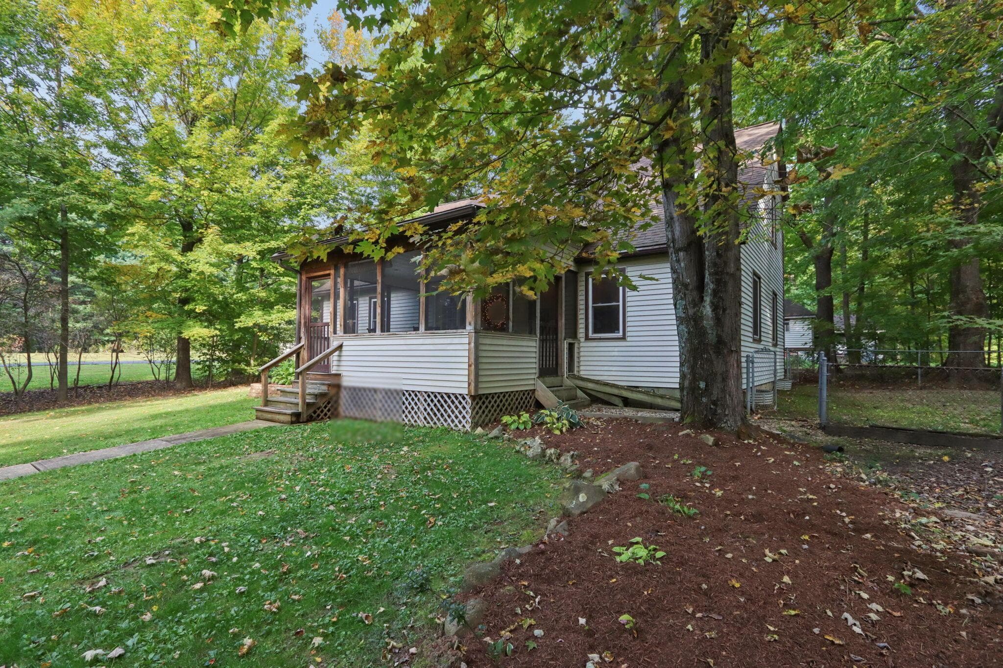 Exterior side with freshly mulched landscaping and lots of mature trees