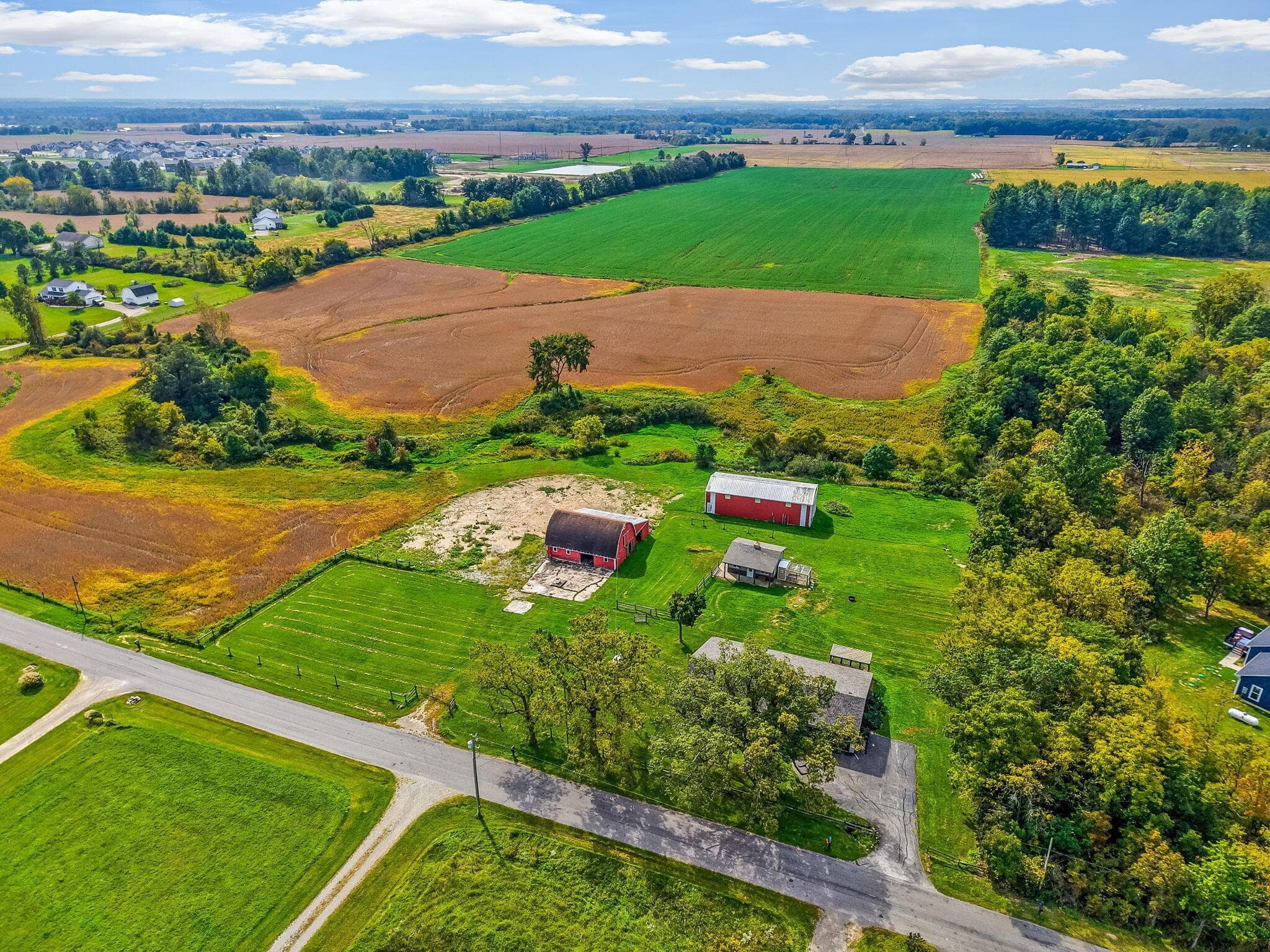 Expansive land parcel featuring multiple outbuildings, open fields, and mature trees