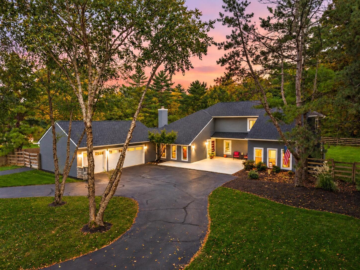 Two-story contemporary residence with a multi-car garage, paved driveway, and mature landscaping