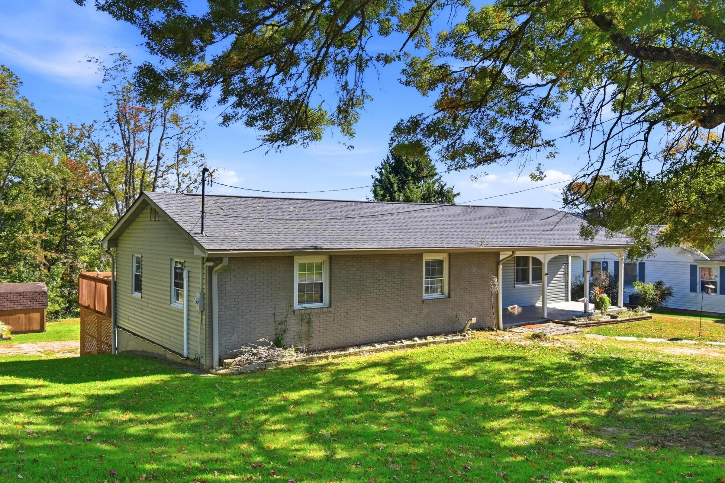 Single-story residence featuring a shingle roof, light-colored siding, and a stone-finish foundation