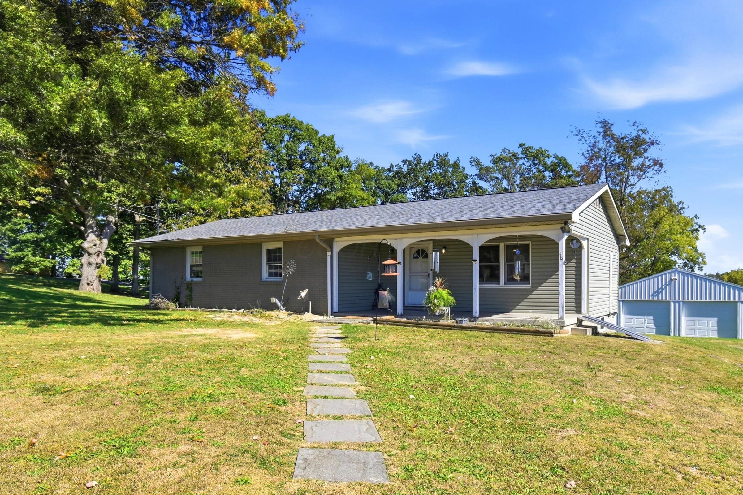 Ranch-style residence featuring a covered front porch, stone pathway, and a detached two-car garage