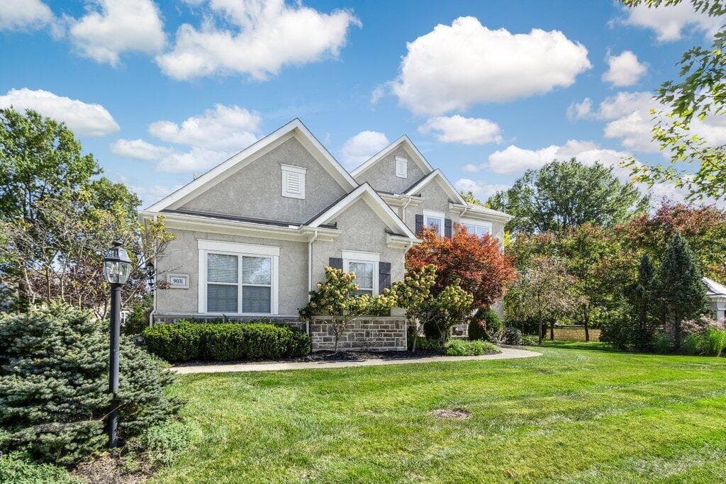 Stucco exterior with stone accenting, multiple gables, and dark window shutters