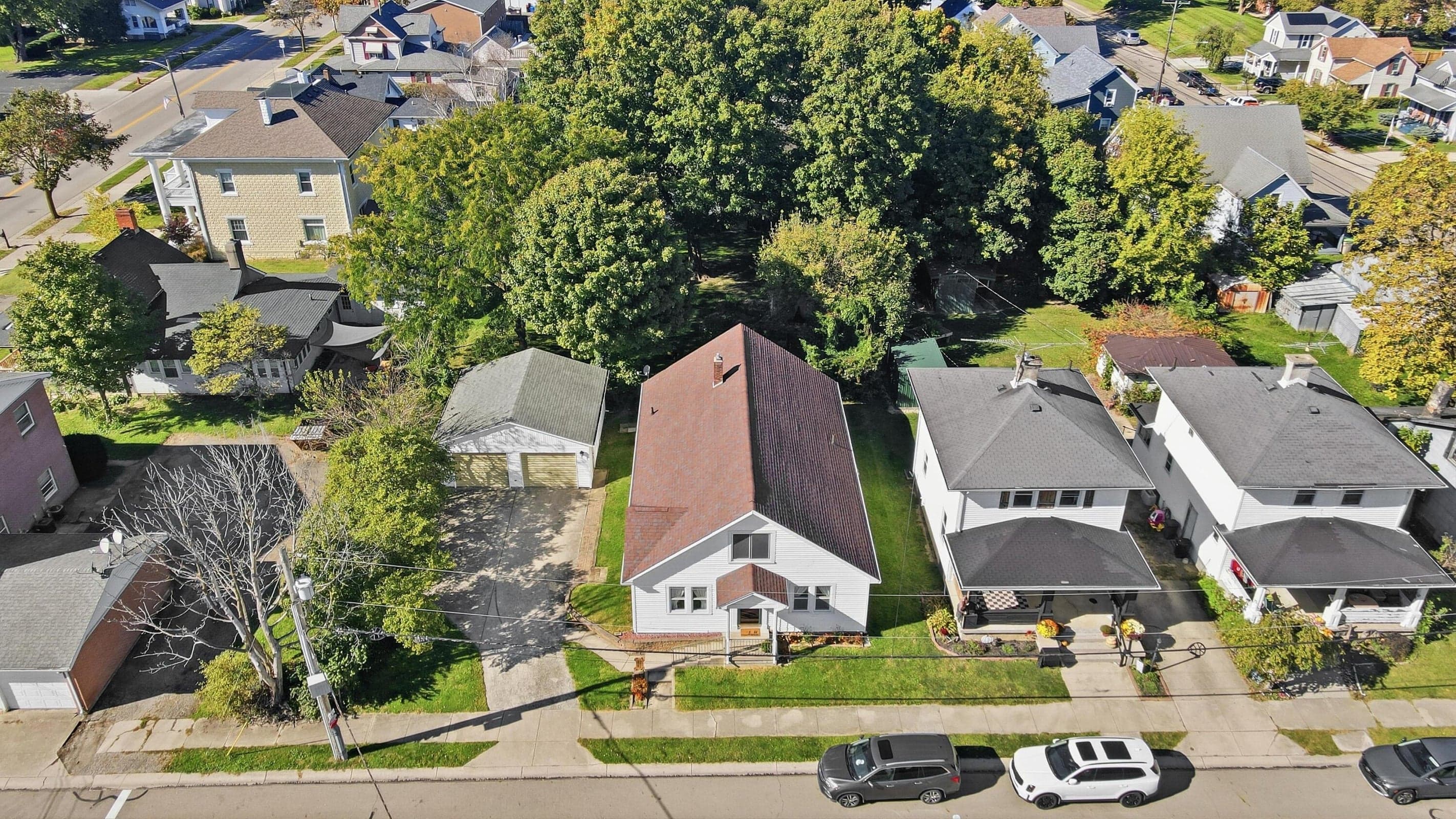 Gable roofline, prominent front entrance, detached two-car garage, mature landscaping, and an established neighborhood setting