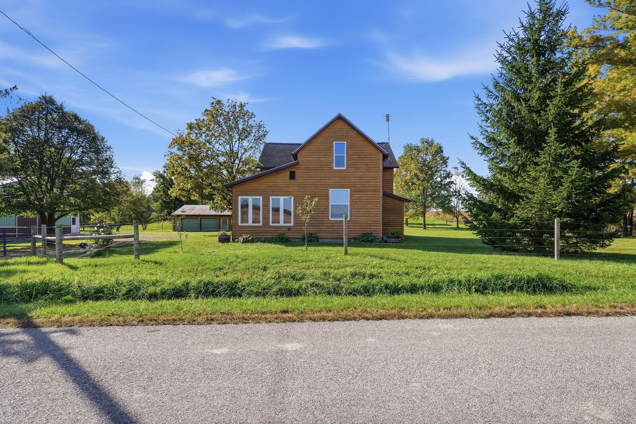 Two-story home with horizontal wood siding, multiple windows, asphalt shingle roofing, and an expansive lawn