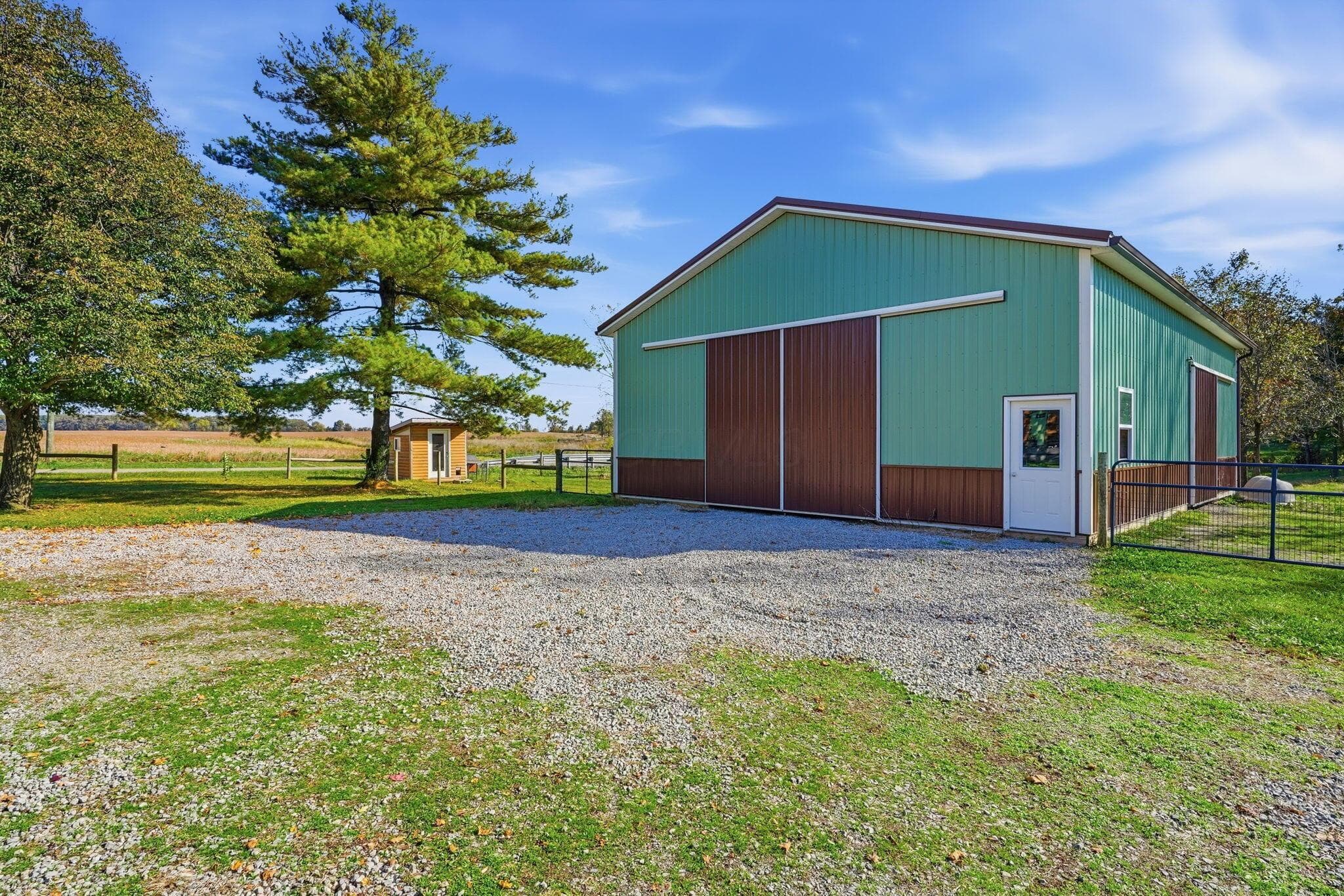 Detached outbuilding featuring metal siding, large sliding barn doors, a man door, and a gravel driveway