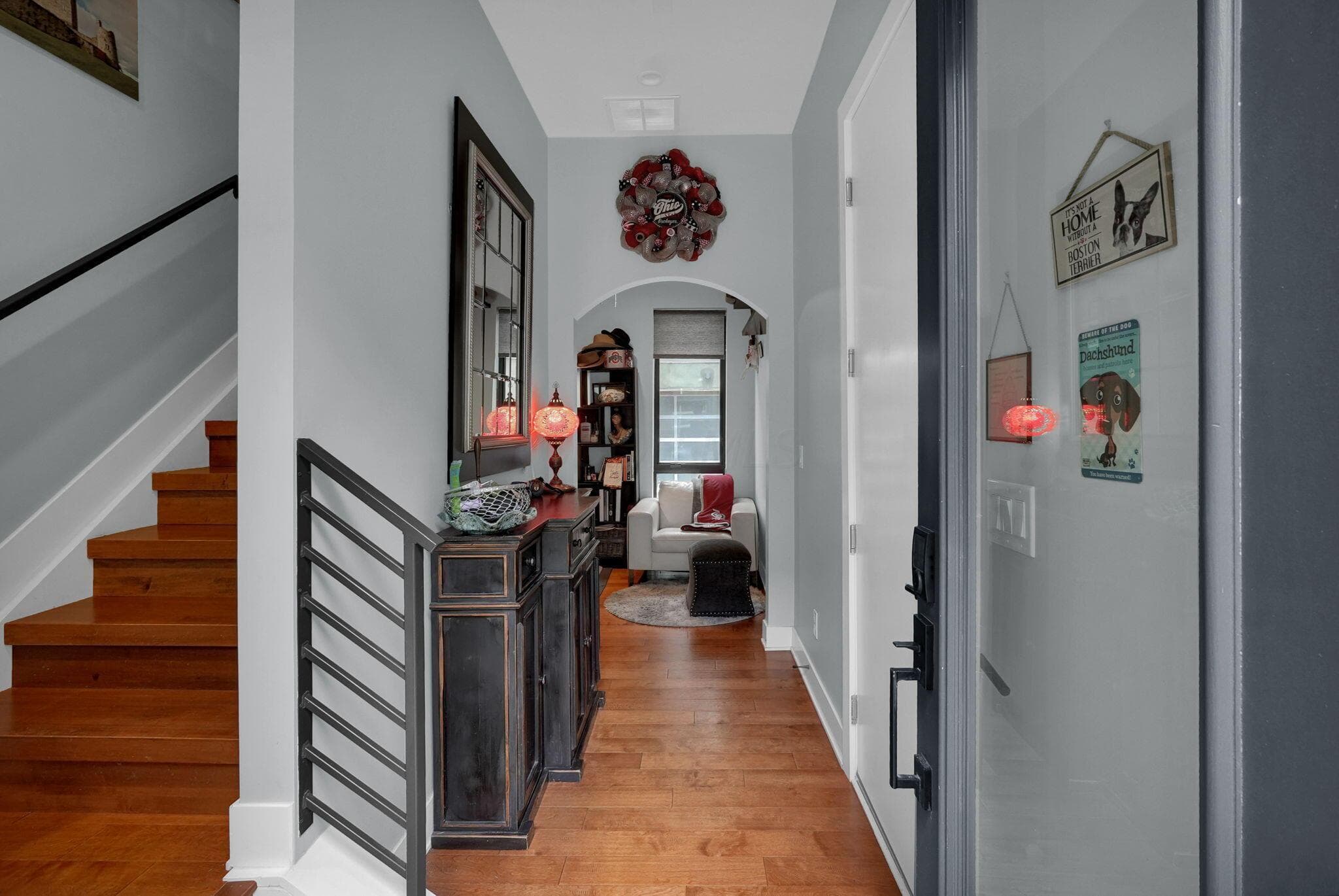 Hardwood flooring, arched doorway, staircase with wood treads and black metal railing, white wall paint