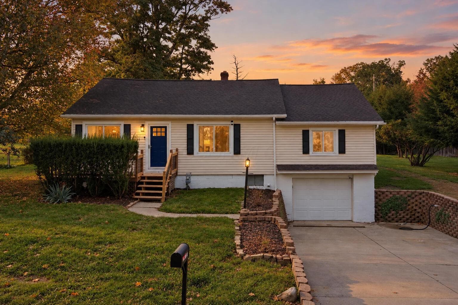 Single-family residence with light-toned siding, a dark shingle roof, and a prominent attached garage in fall