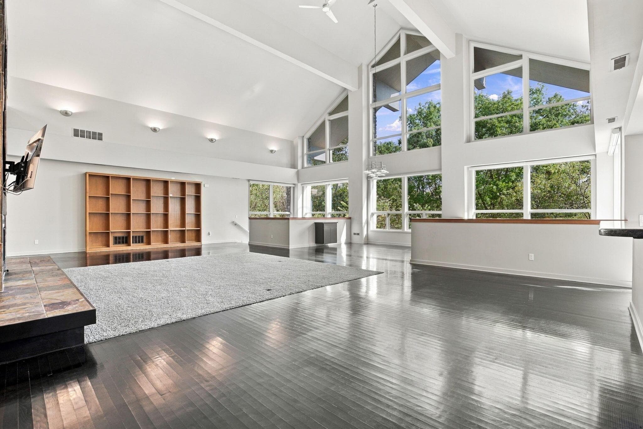 Vaulted ceilings, multi-level windows, built-in shelving, tile-surround fireplace hearth, and wood-finish flooring