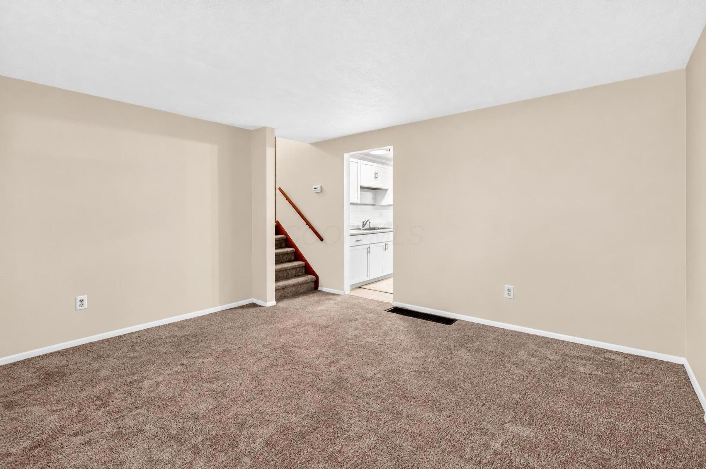 Neutral-toned walls, carpeted flooring, and a wooden handrail on the staircase