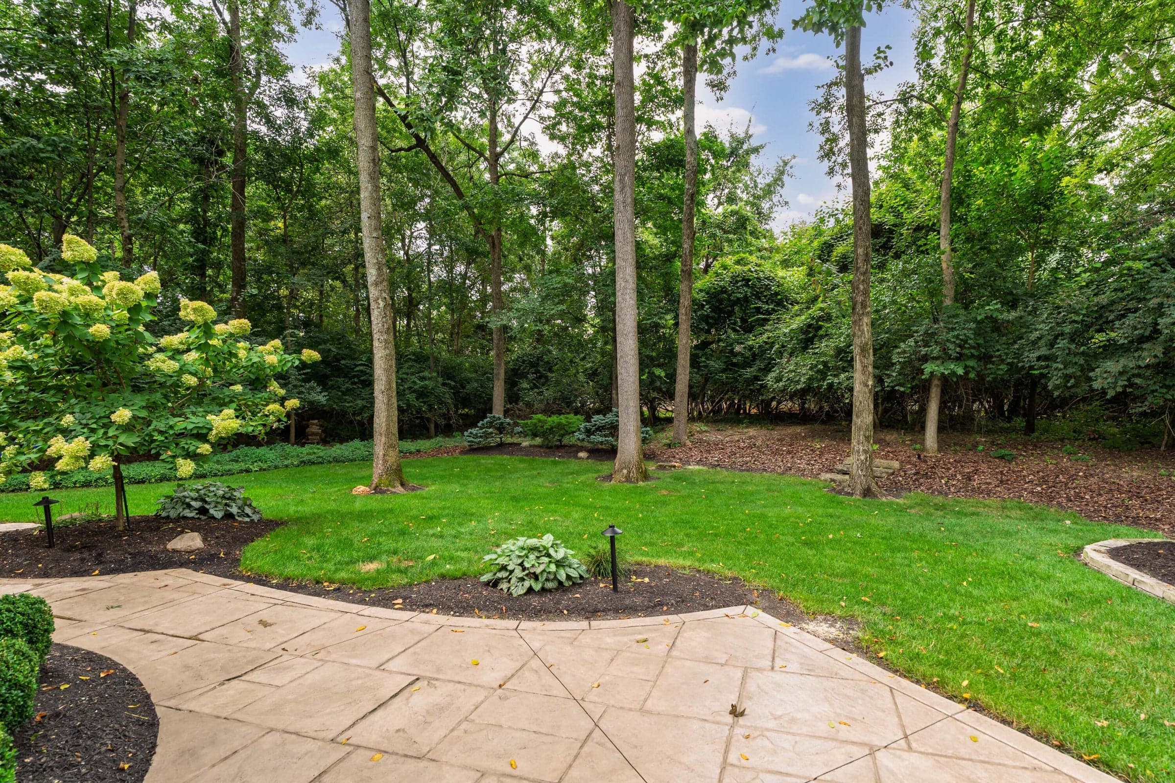 Large Stone paver patio with meticulously cared for plants and yard.