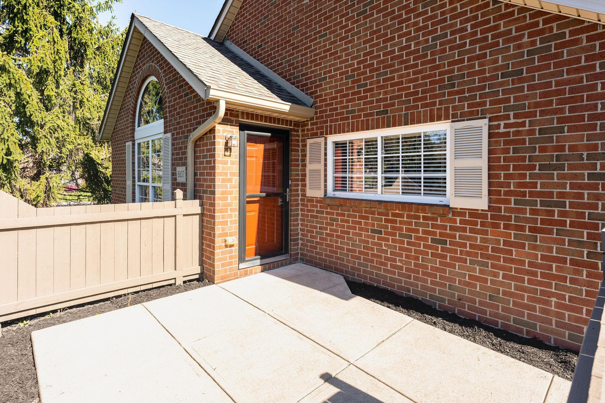 Brick exterior and concrete patio features a sunny spot to extend your living space outside.