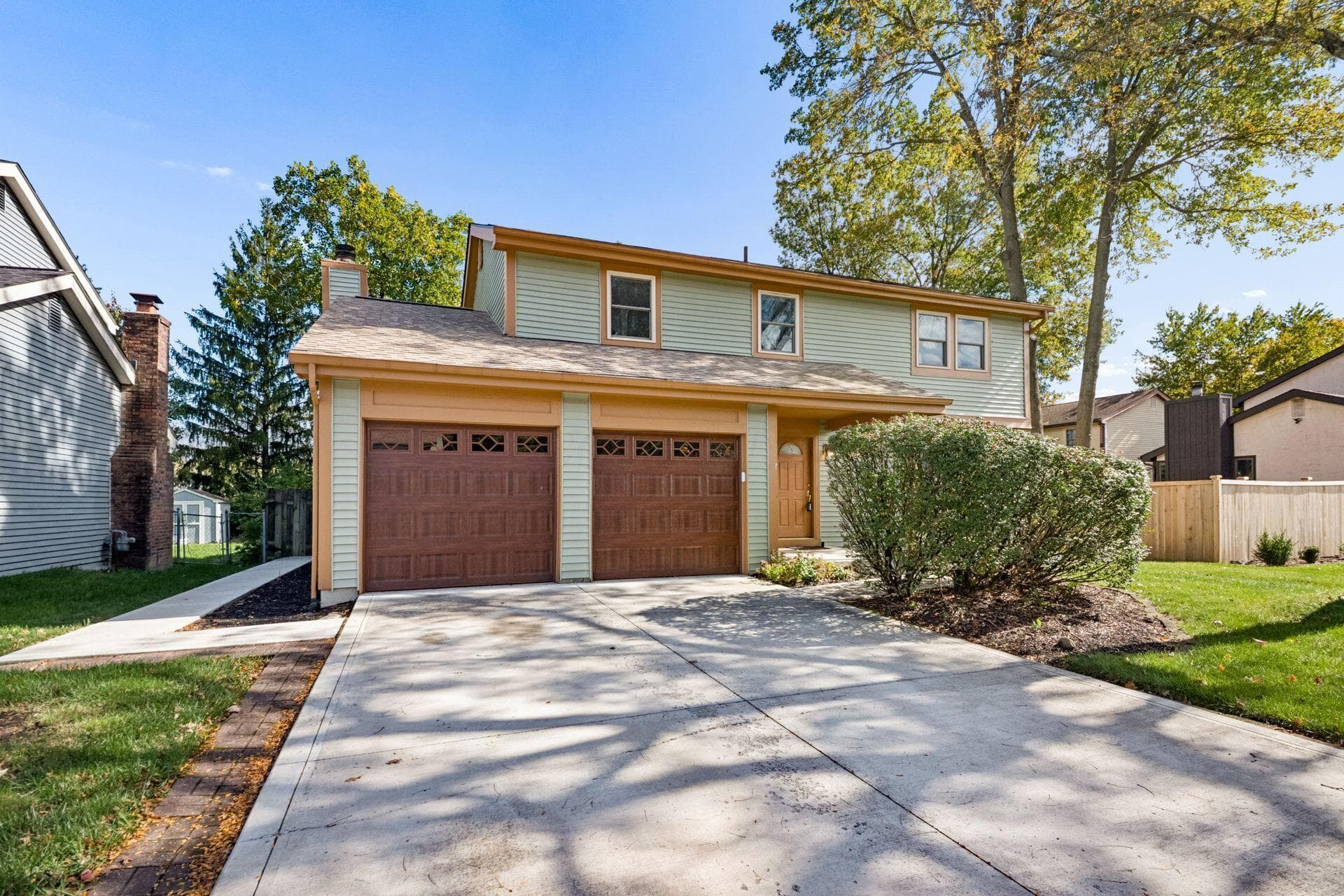 Attractive two-story home in Woodside Green featuring new siding, mature landscaping, and an attached two-car garage.