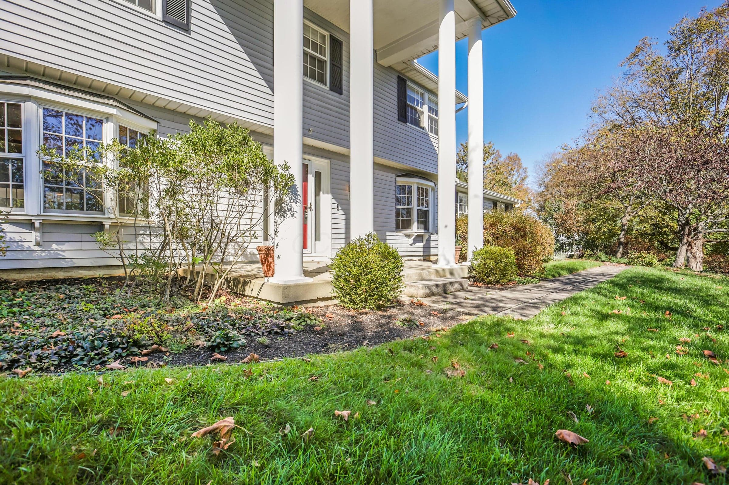 Two-story Colonial exterior featuring horizontal lap siding, a grand covered porch with full-height columns, and multiple bay windows