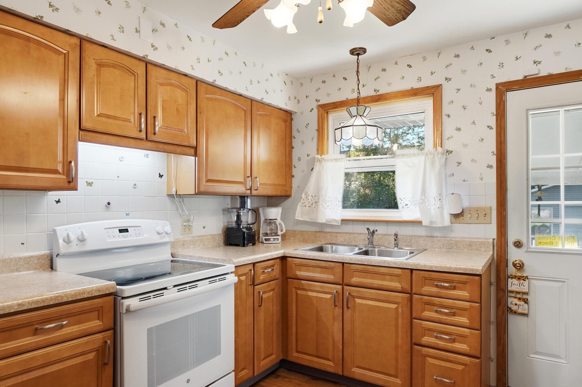 Wood cabinets, a glass-top range, and a double sink under the window.