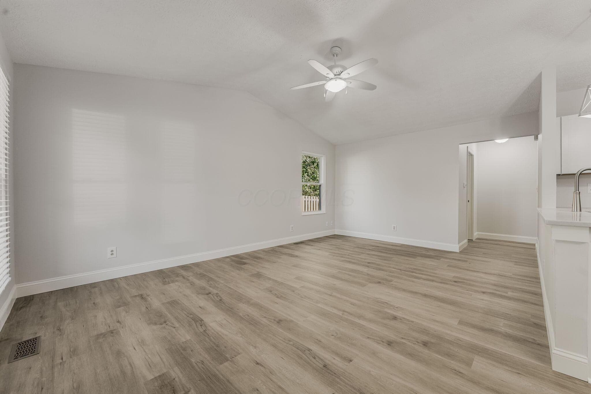 Vaulted ceilings, wood-finish flooring, and a central ceiling fan with integrated lighting