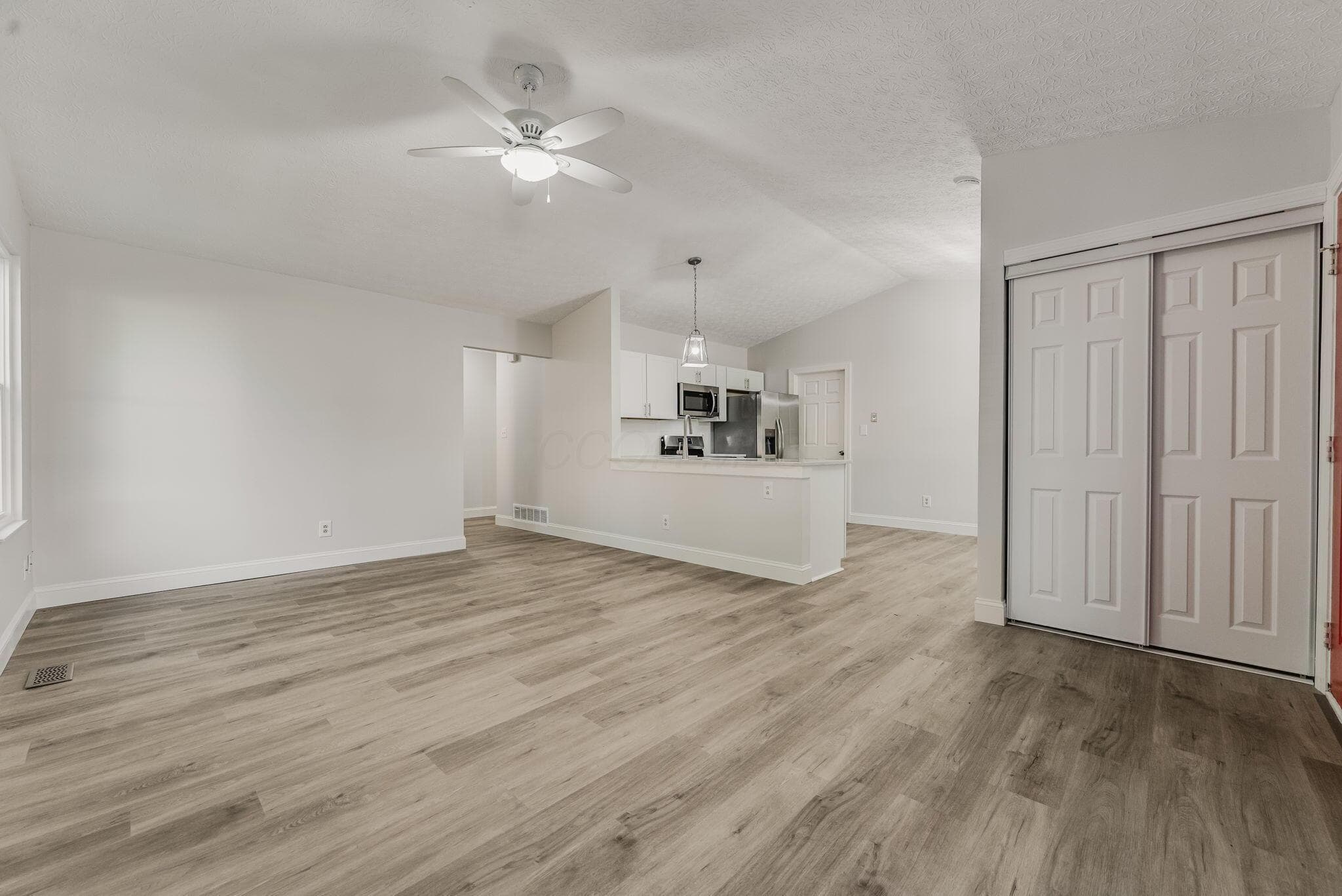 Vaulted ceilings featuring a central ceiling fan, wood-finish flooring, and white interior doors with paneled detailing